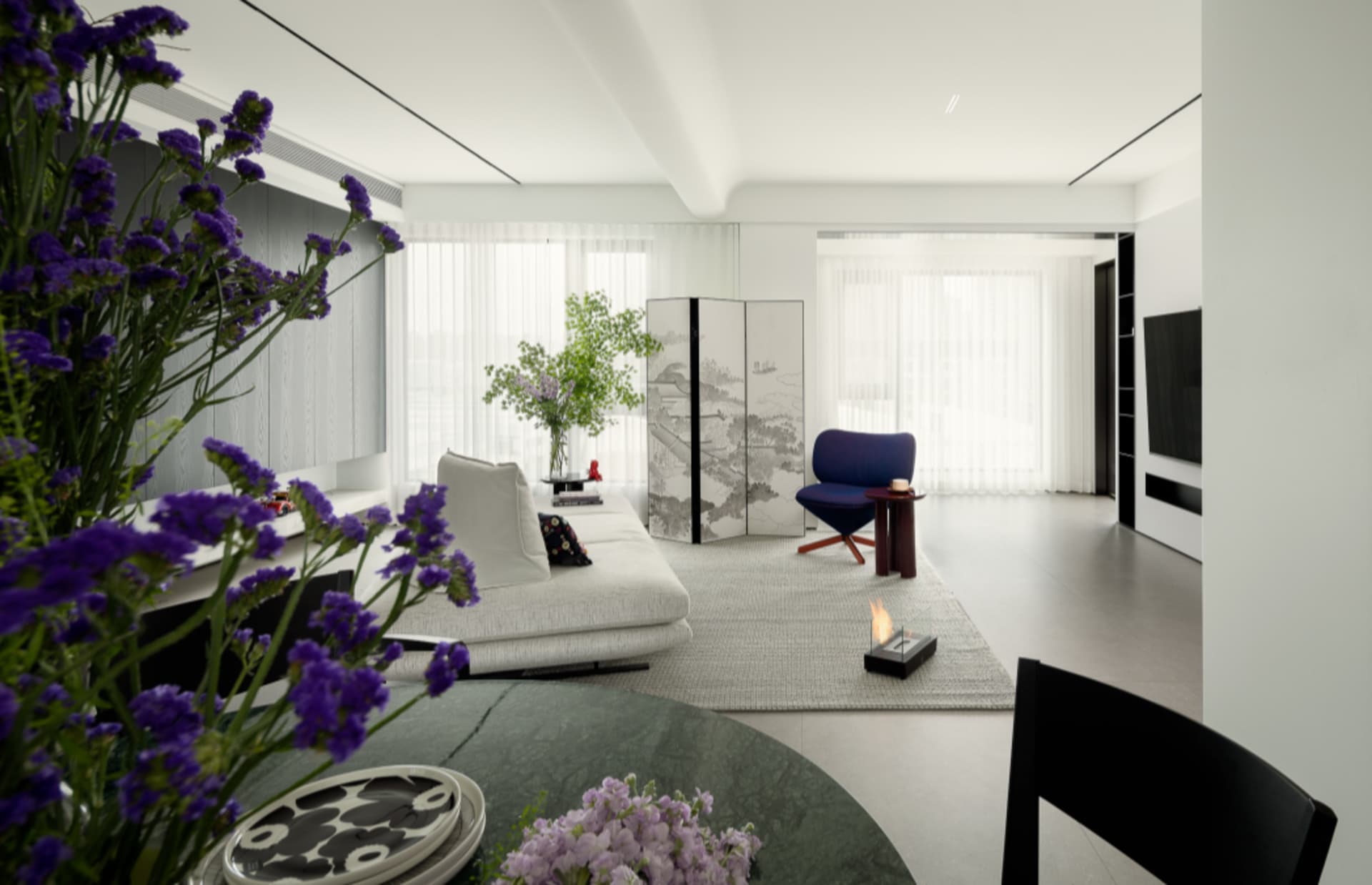 Modern living room featuring a mix of white, blue, and purple decorative elements, including a white sofa, blue armchair, and