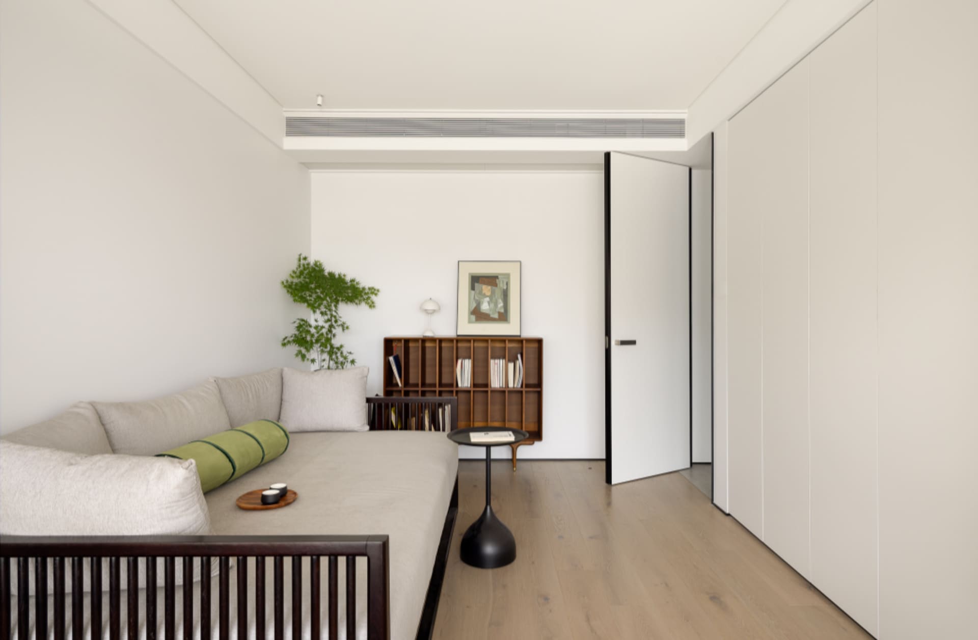 A modern minimalist living room featuring a comfortable sofa, a wooden coffee table, and a sleek metal bookshelf.