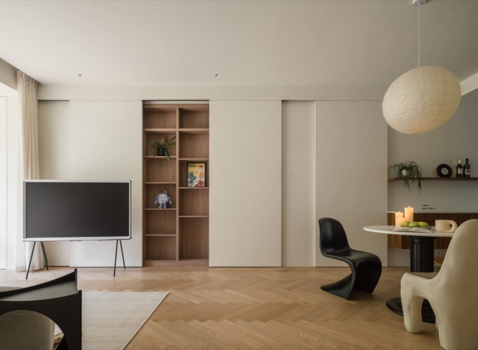 A minimalist living room with a flat-screen TV, bookshelves, and chairs designed with wood tiles.