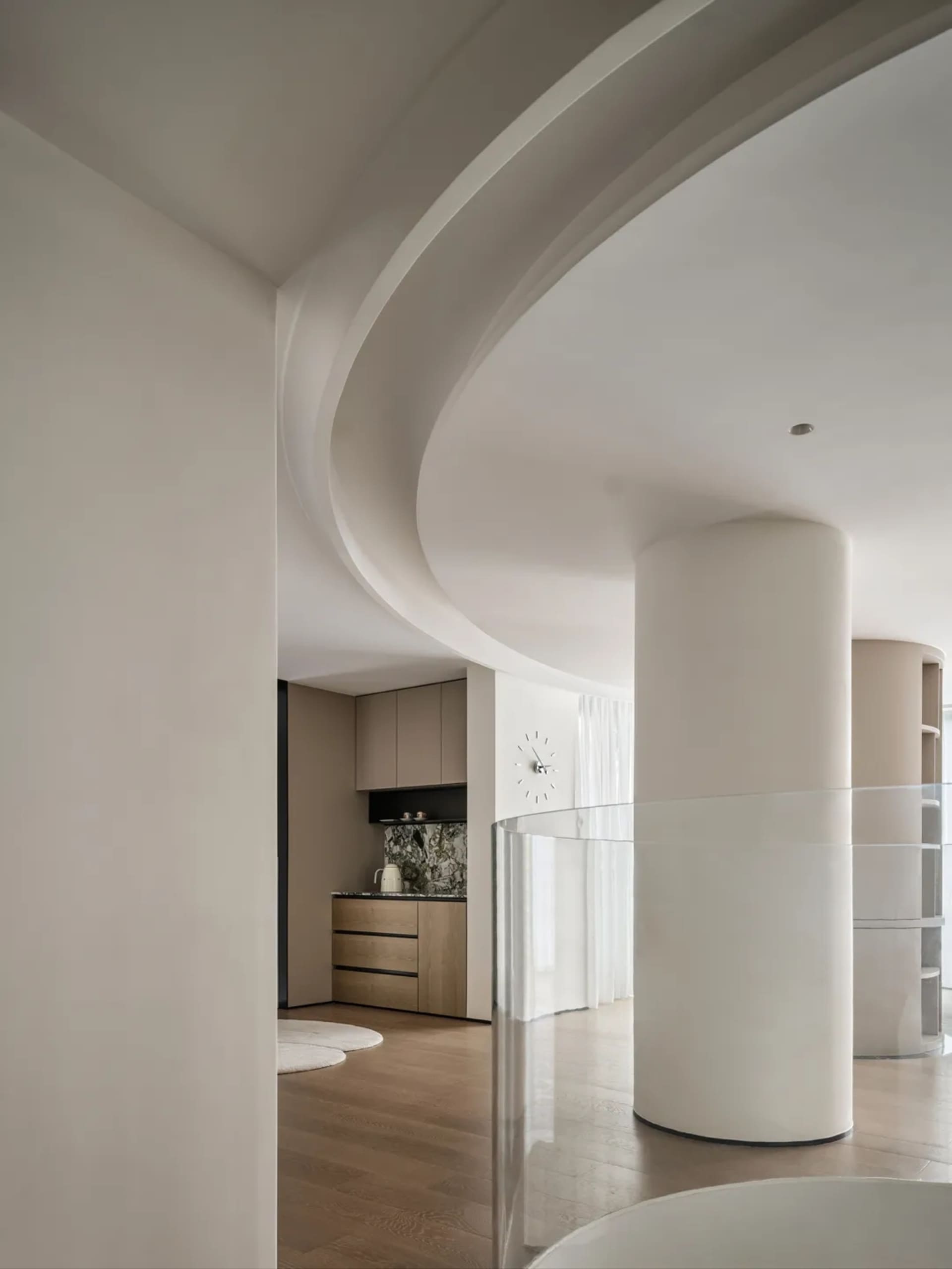 A modern, minimalist kitchen with white marble countertops and wooden cabinets.