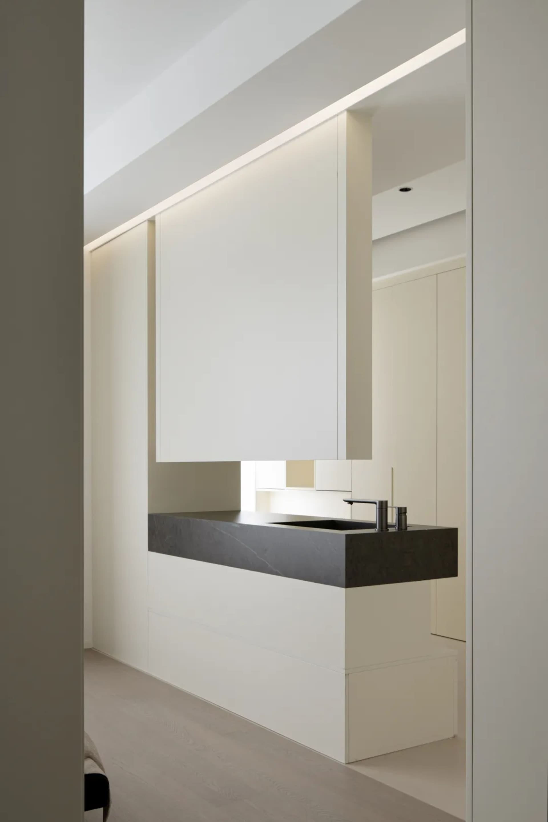 A modern kitchen with minimalist design featuring black concrete countertops and wooden cabinets.