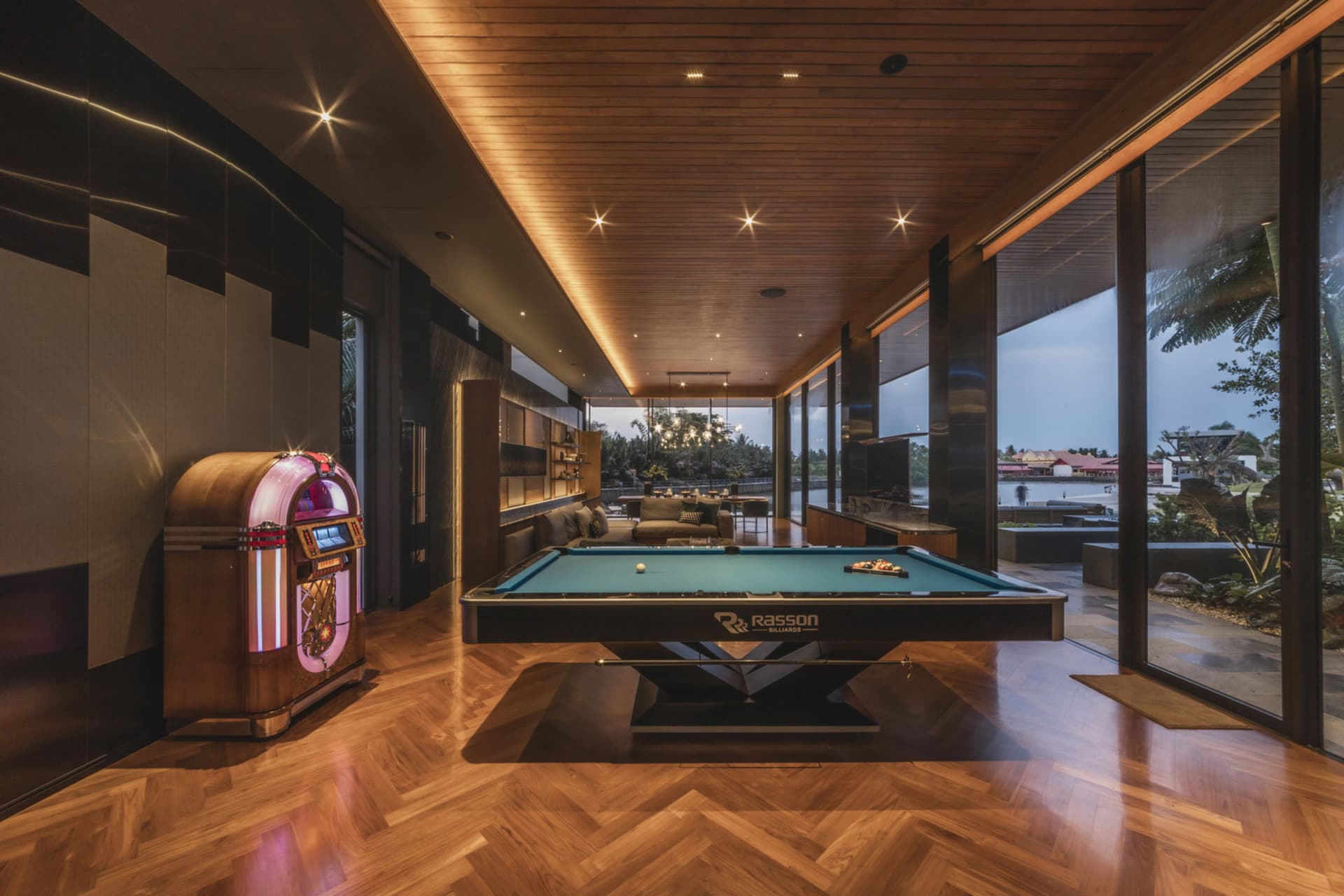 Well-lit, modern game room featuring a pool table, jukebox, and comfortable seating.