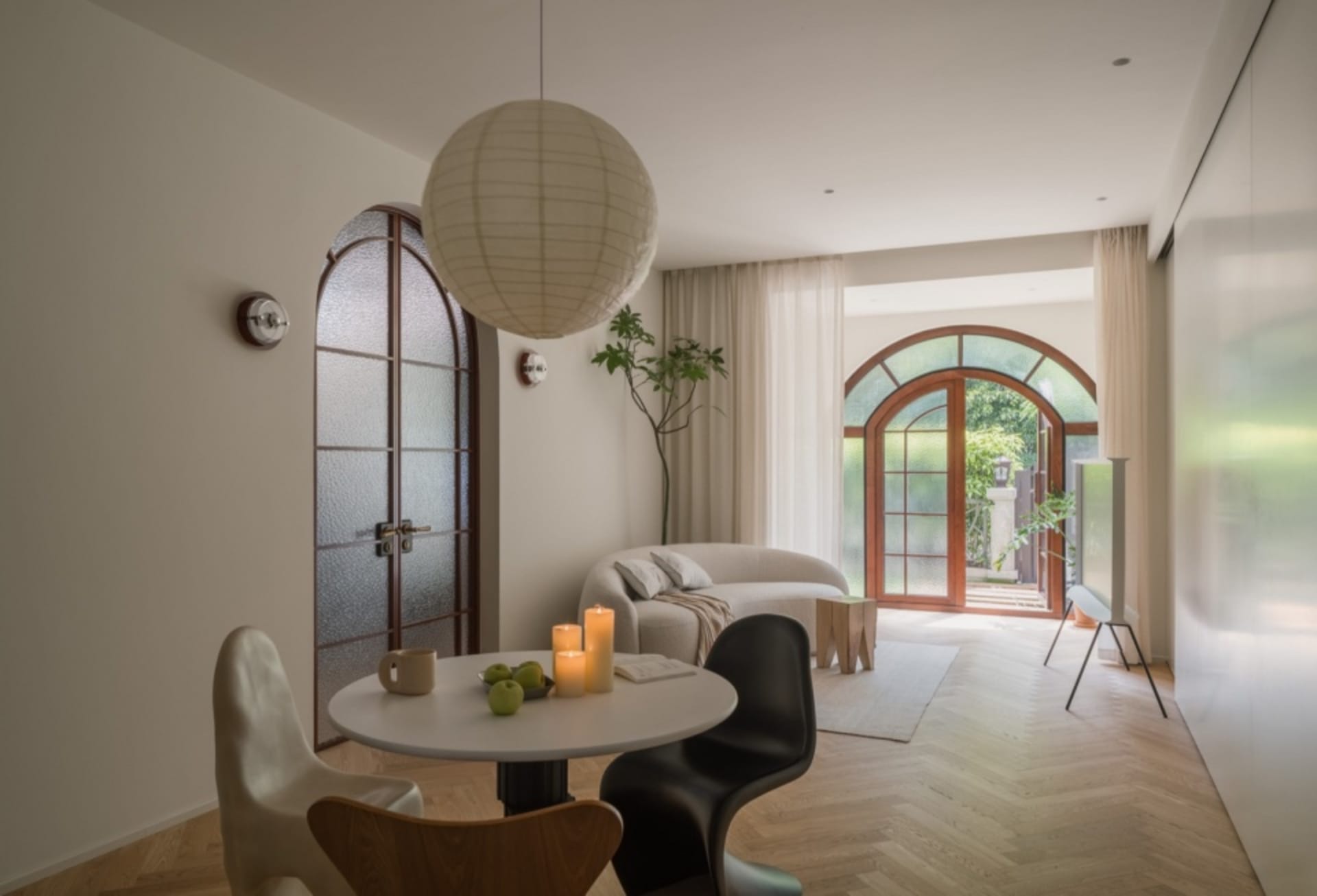 A modern living room with wooden furniture, floor-to-ceiling curtains, and an arched window.