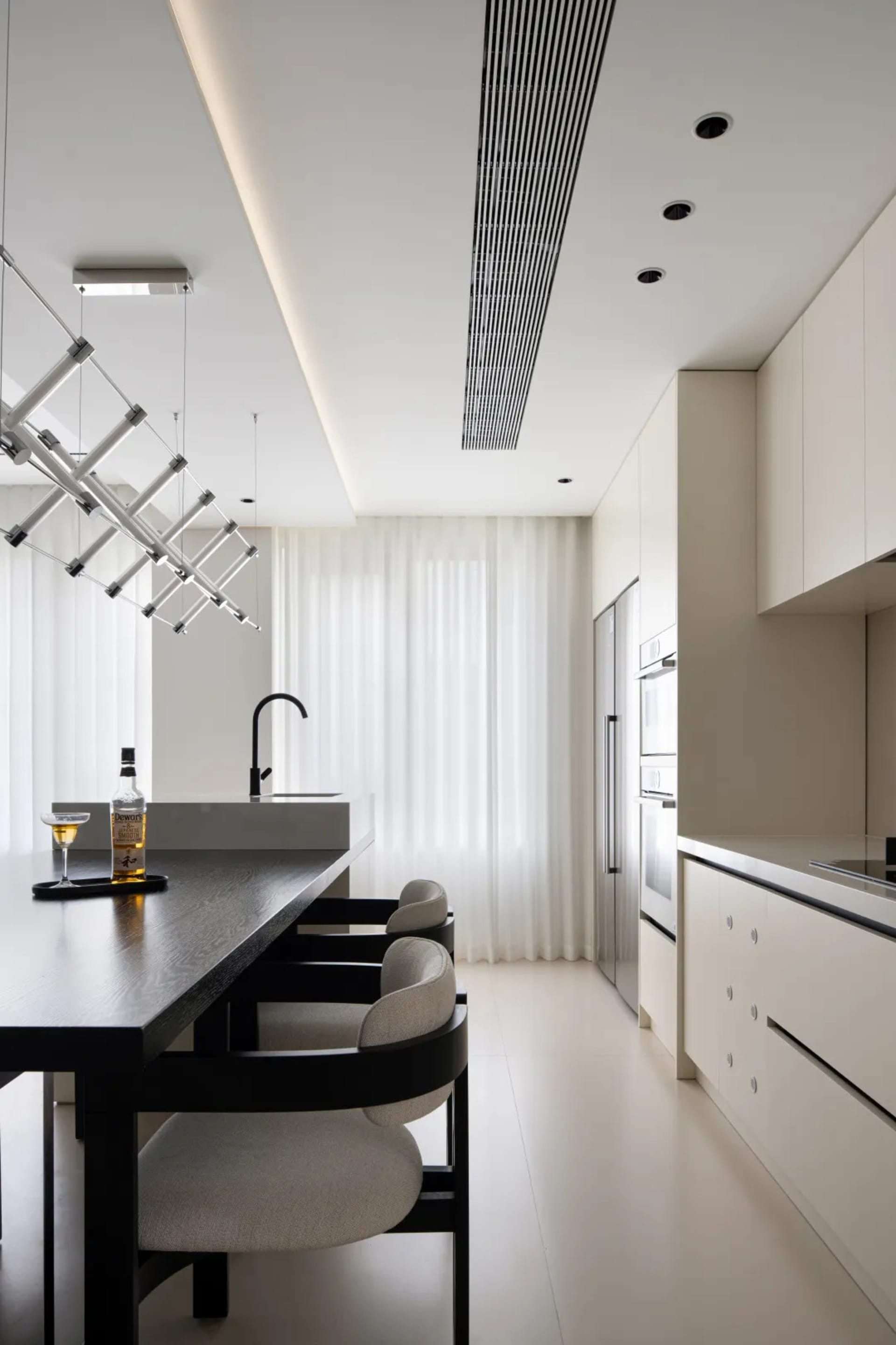 Modern kitchen featuring minimalist design with white materials, sleek countertops, and contemporary lighting.