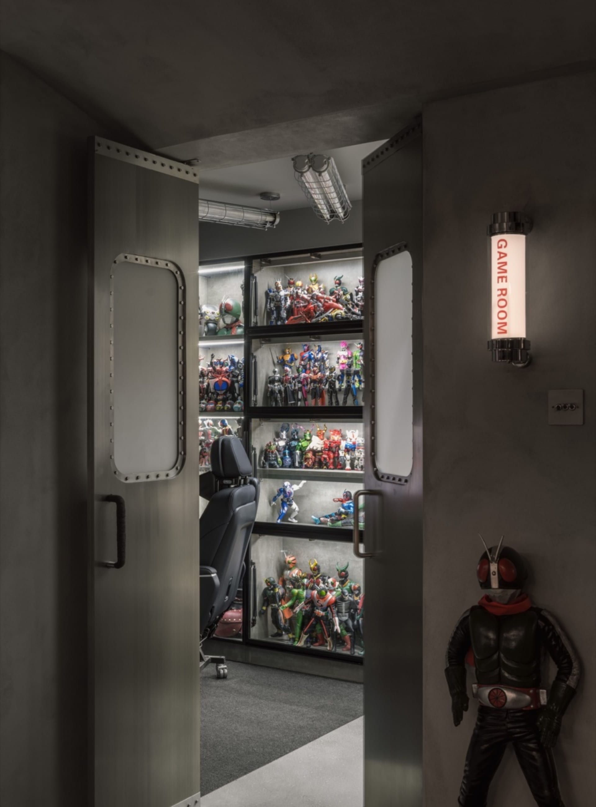 A sleek, industrial-style game room with metallic walls and shelves filled with various action figures.
