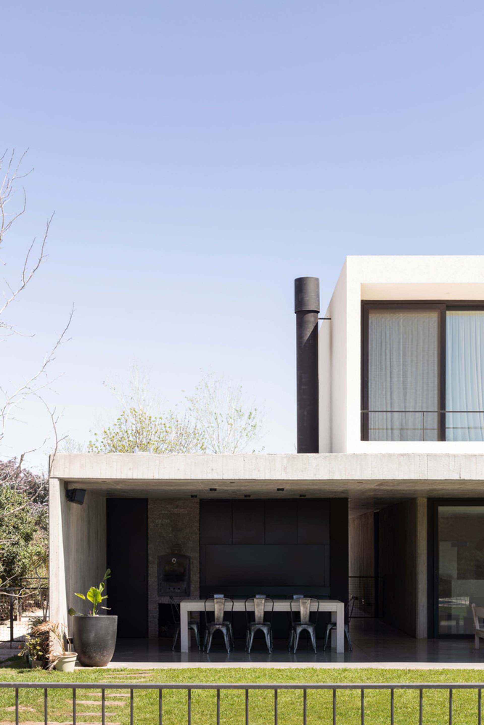 Modern exterior residential space with concrete walls and a black chimney.