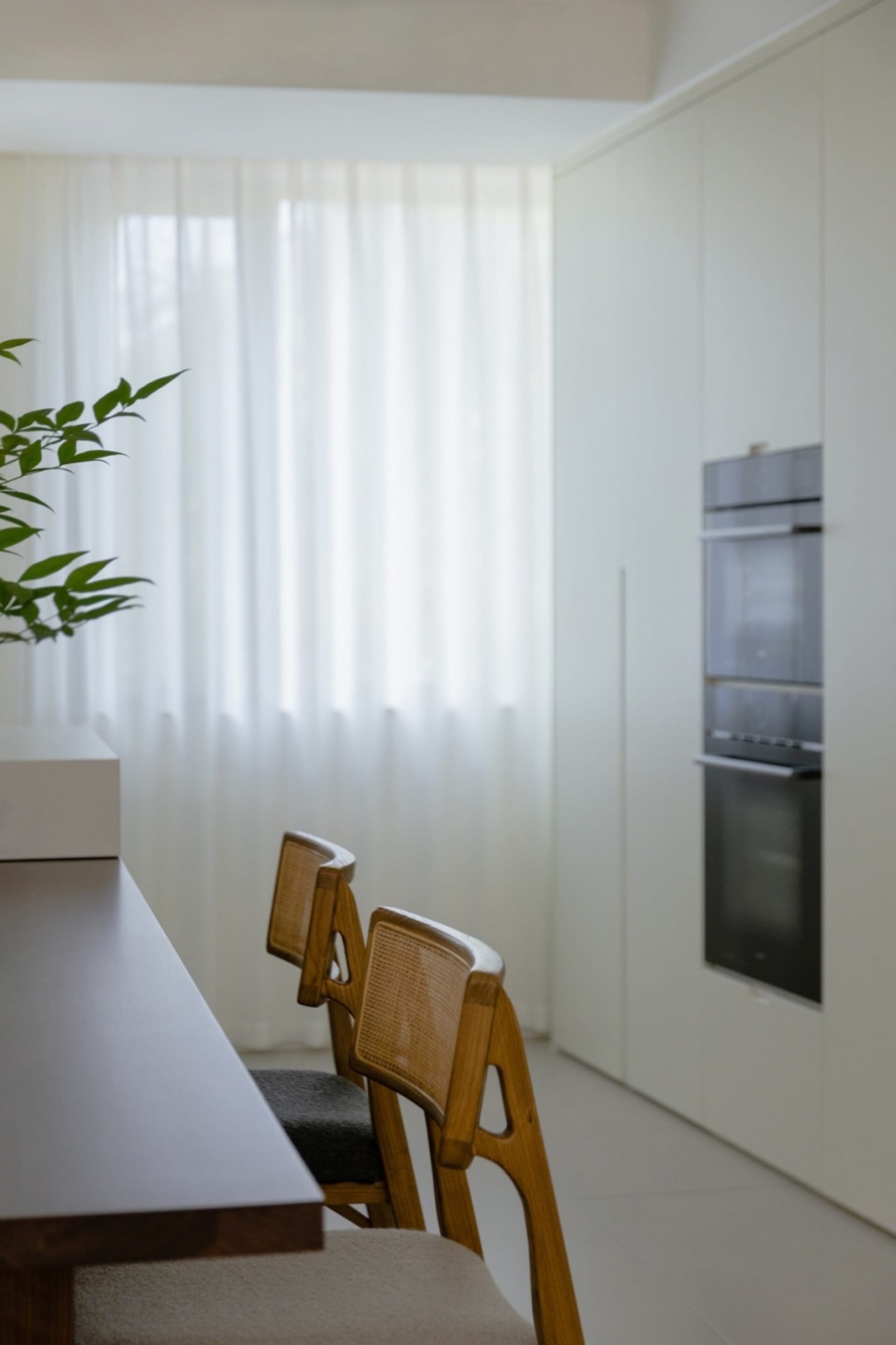 Modern kitchen with wooden furniture and glass windows, featuring contemporary design elements and sleek appliances.