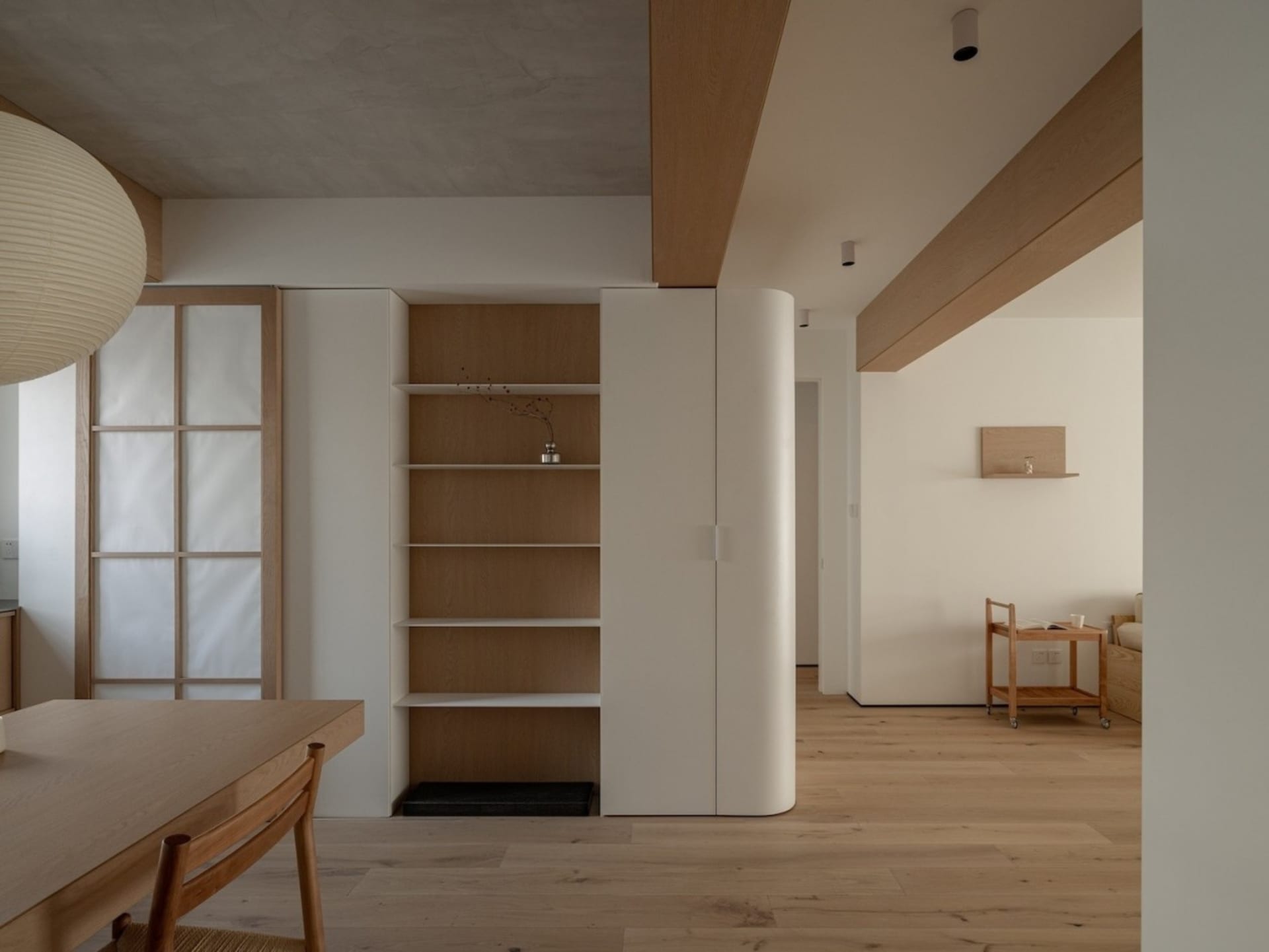 A minimalist apartment featuring a wooden interior with white finishes and natural light.