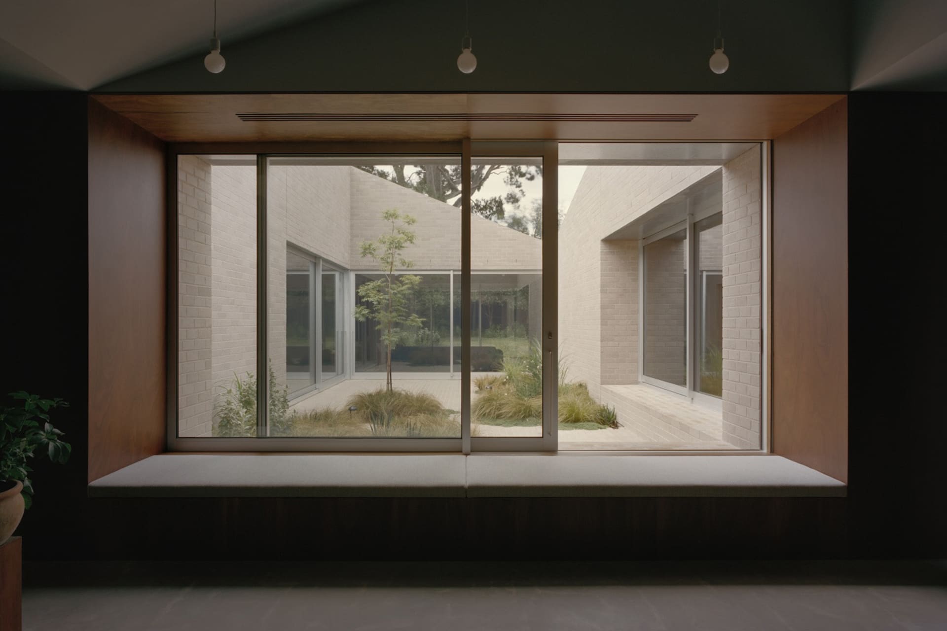 A modern living room with brick and concrete walls, floor-to-ceiling windows, and a minimalist design.