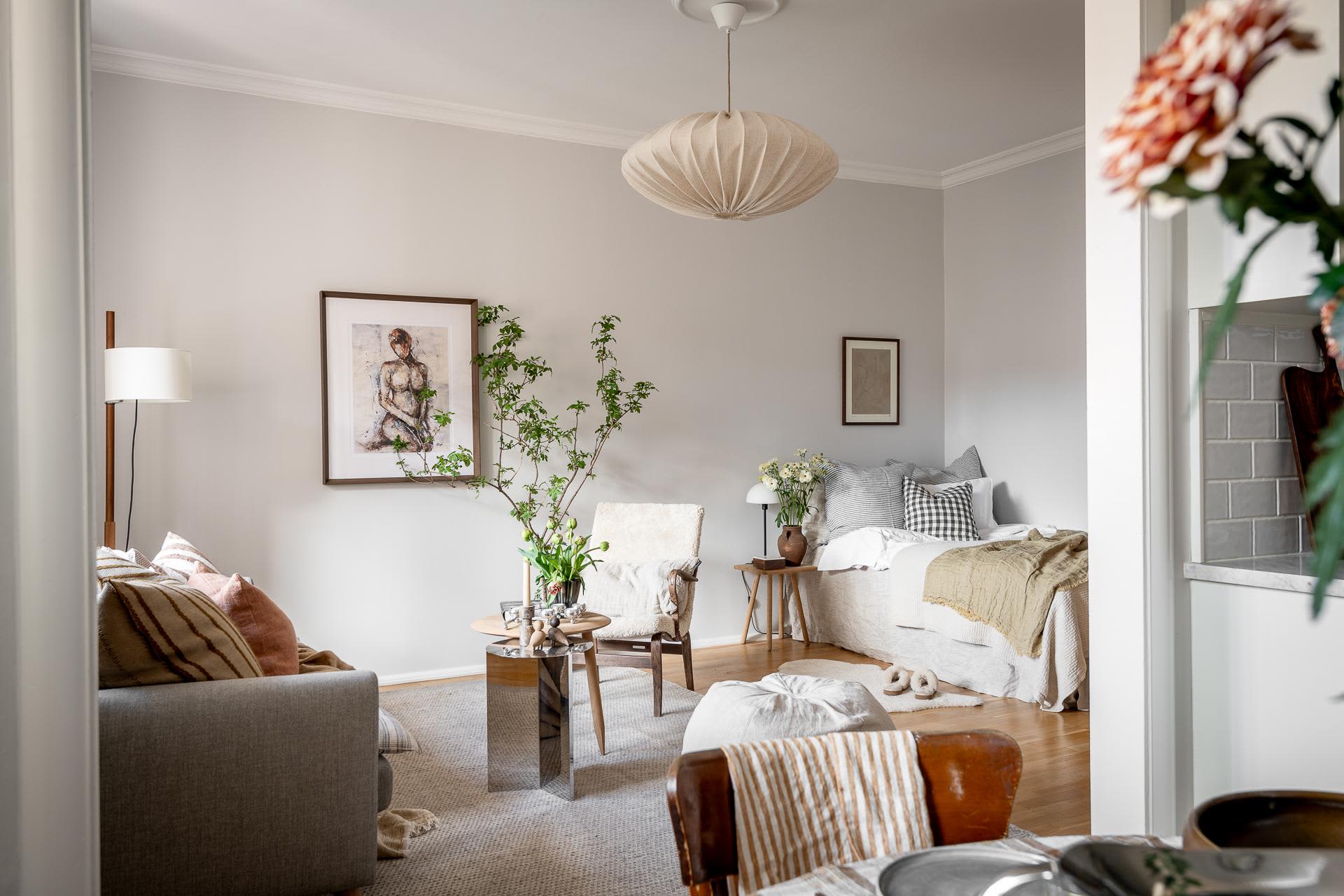 A modern living space with white walls, wooden floors, and fabric furniture, featuring a comfortable seating area, a cozy bed