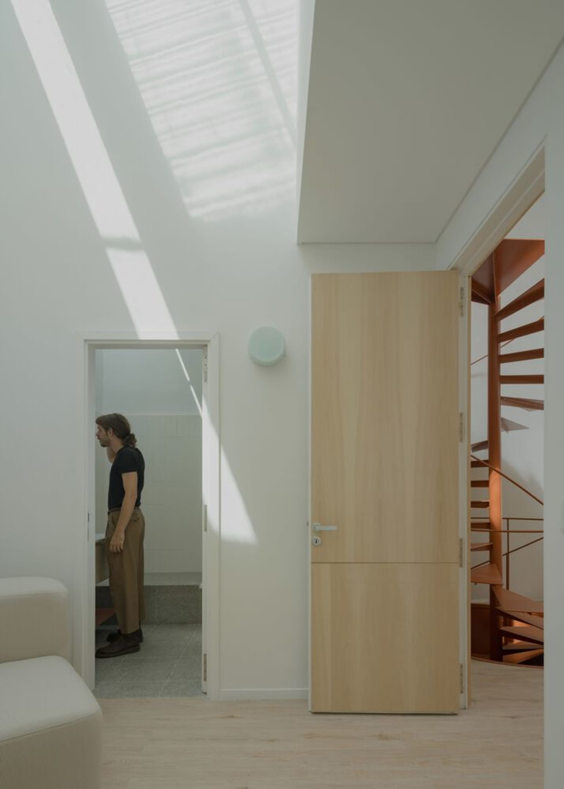 A modern interior space featuring a wooden door with a light wood finish.