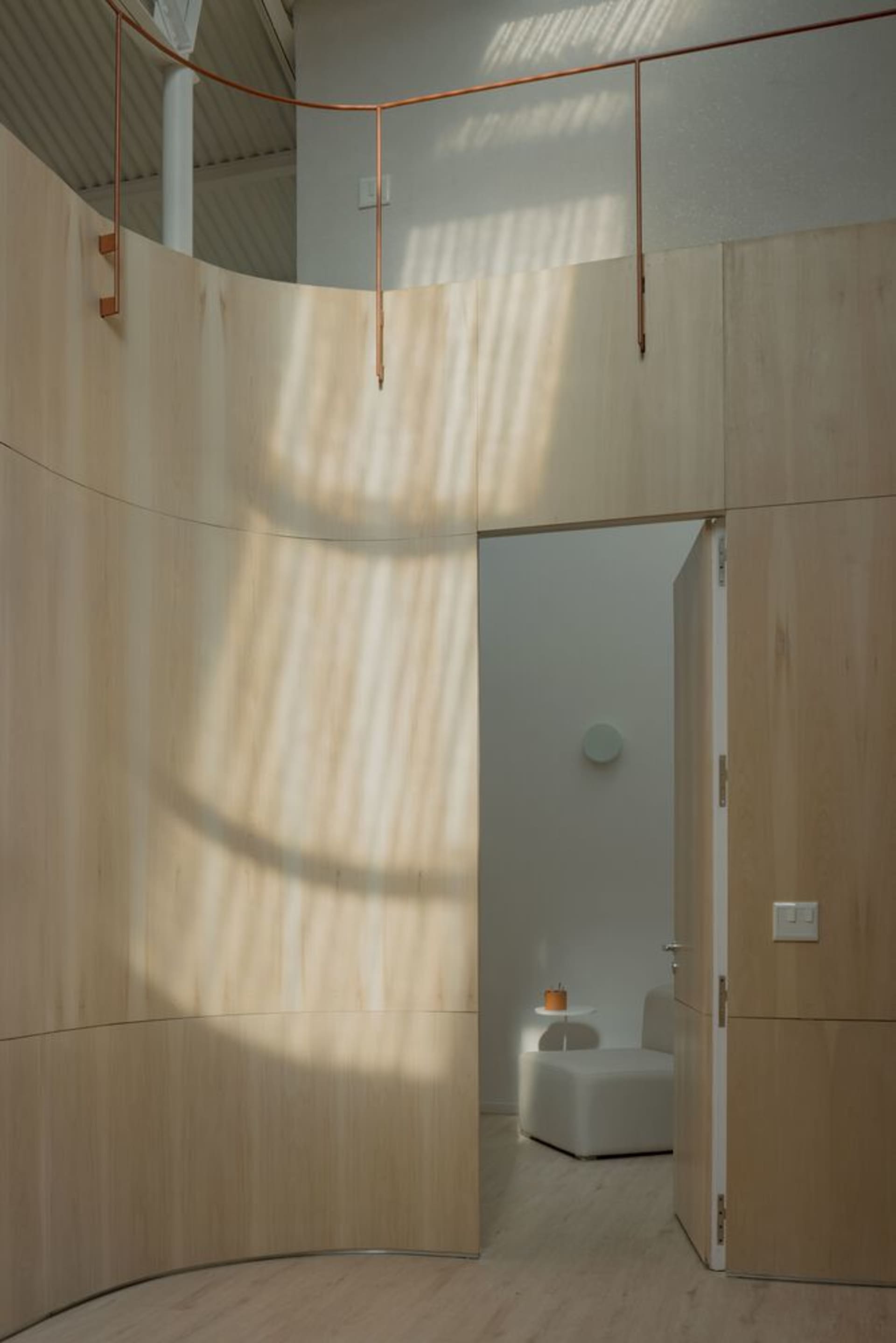A modern living space featuring wood-panelled walls with a white, circular object casting light and shadow patterns.