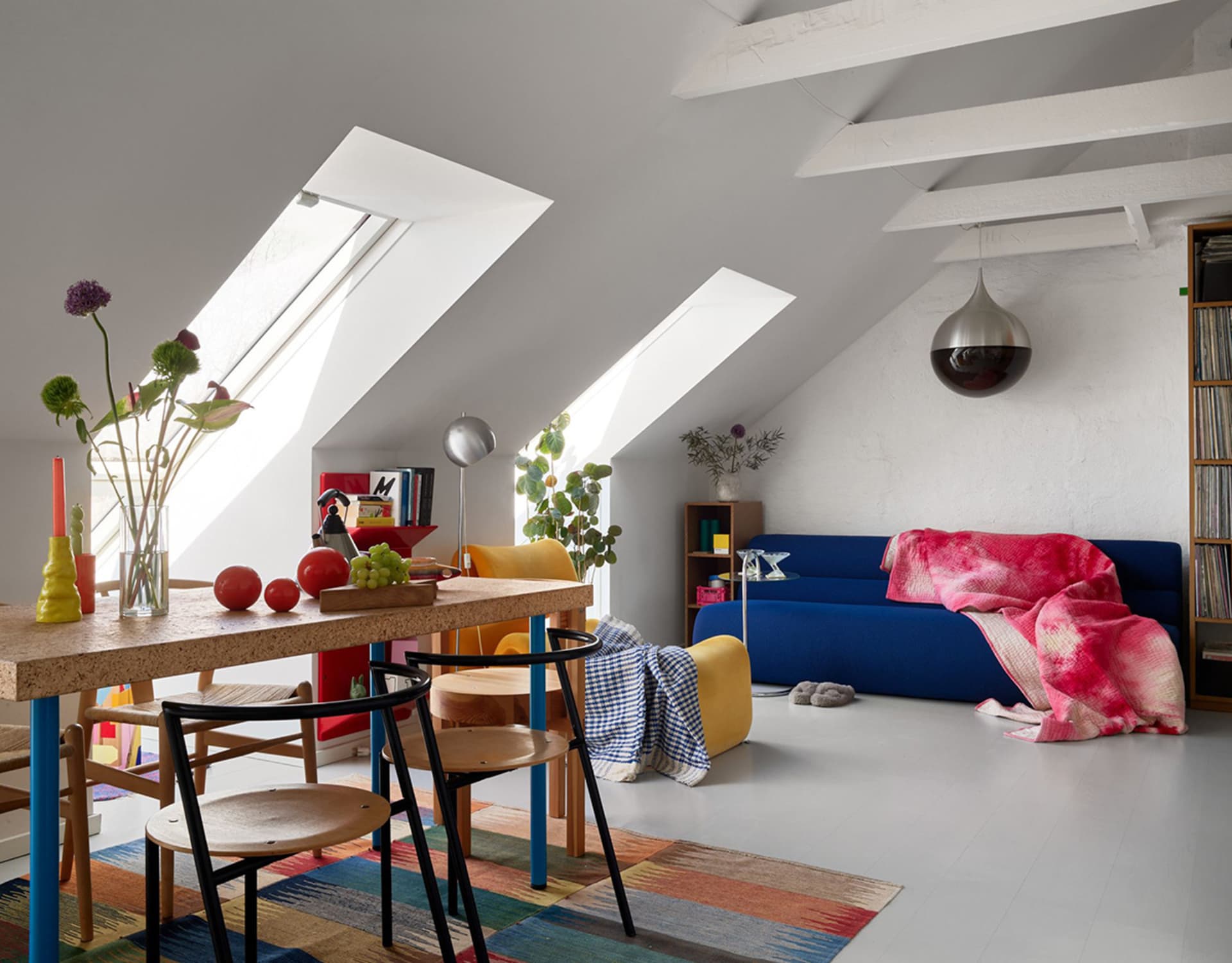 A modern living room featuring a blue sofa, a colorful rug, and concrete walls.