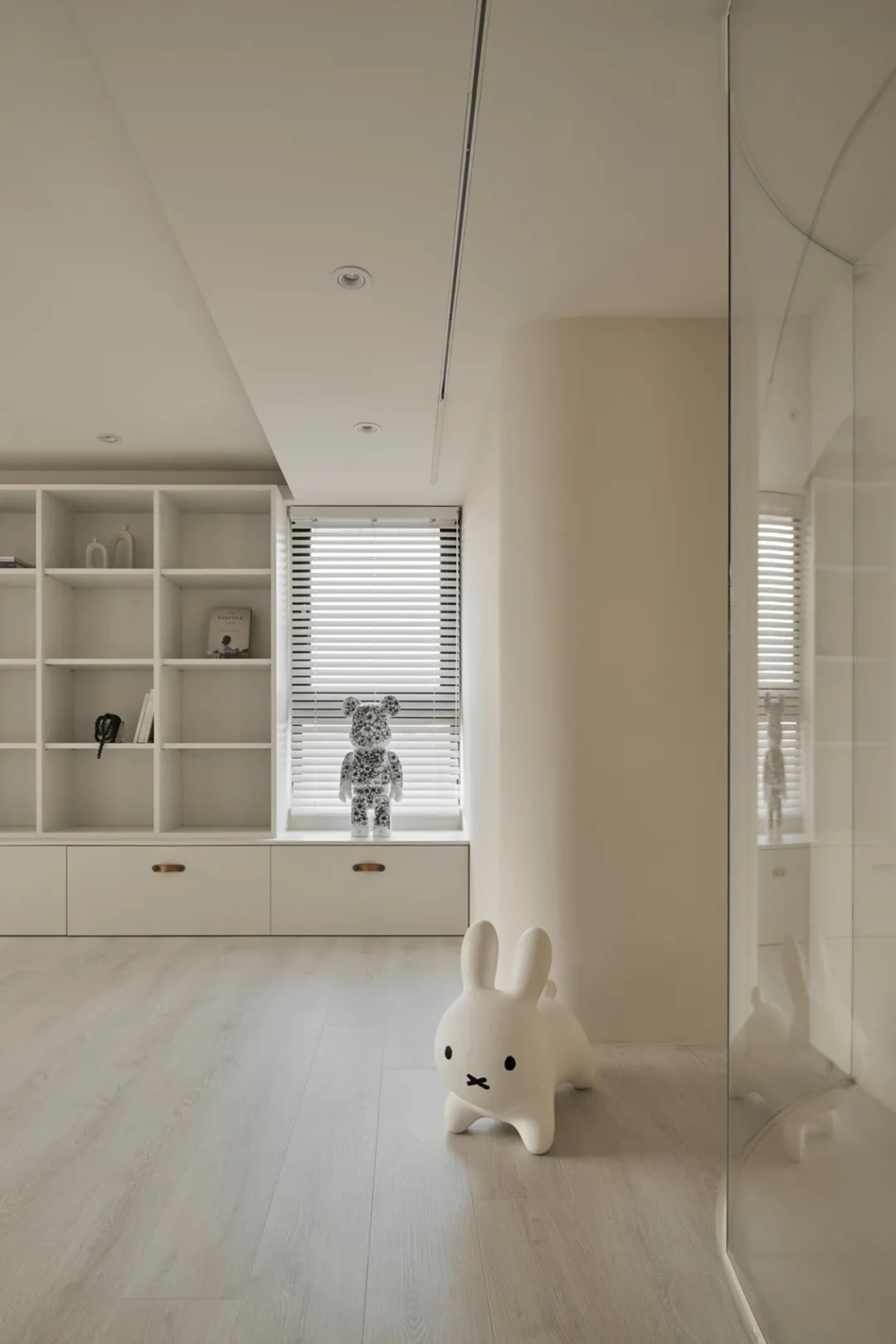 A minimalist playroom with neutral-colored walls, wooden floors, and a white rabbit figure.