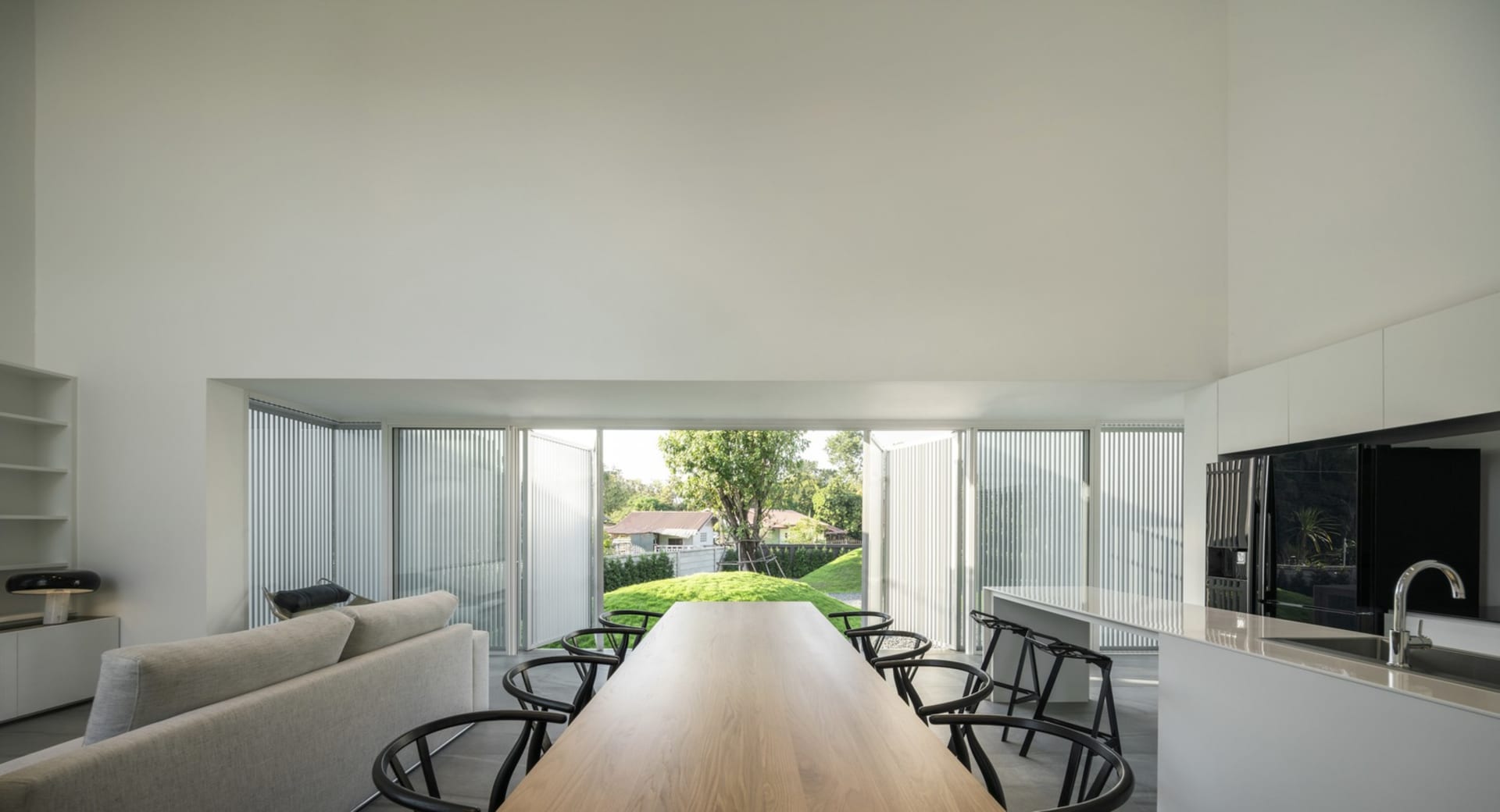Modern residential space featuring sleek, minimalist design with wooden table, glass windows, and metal furniture.