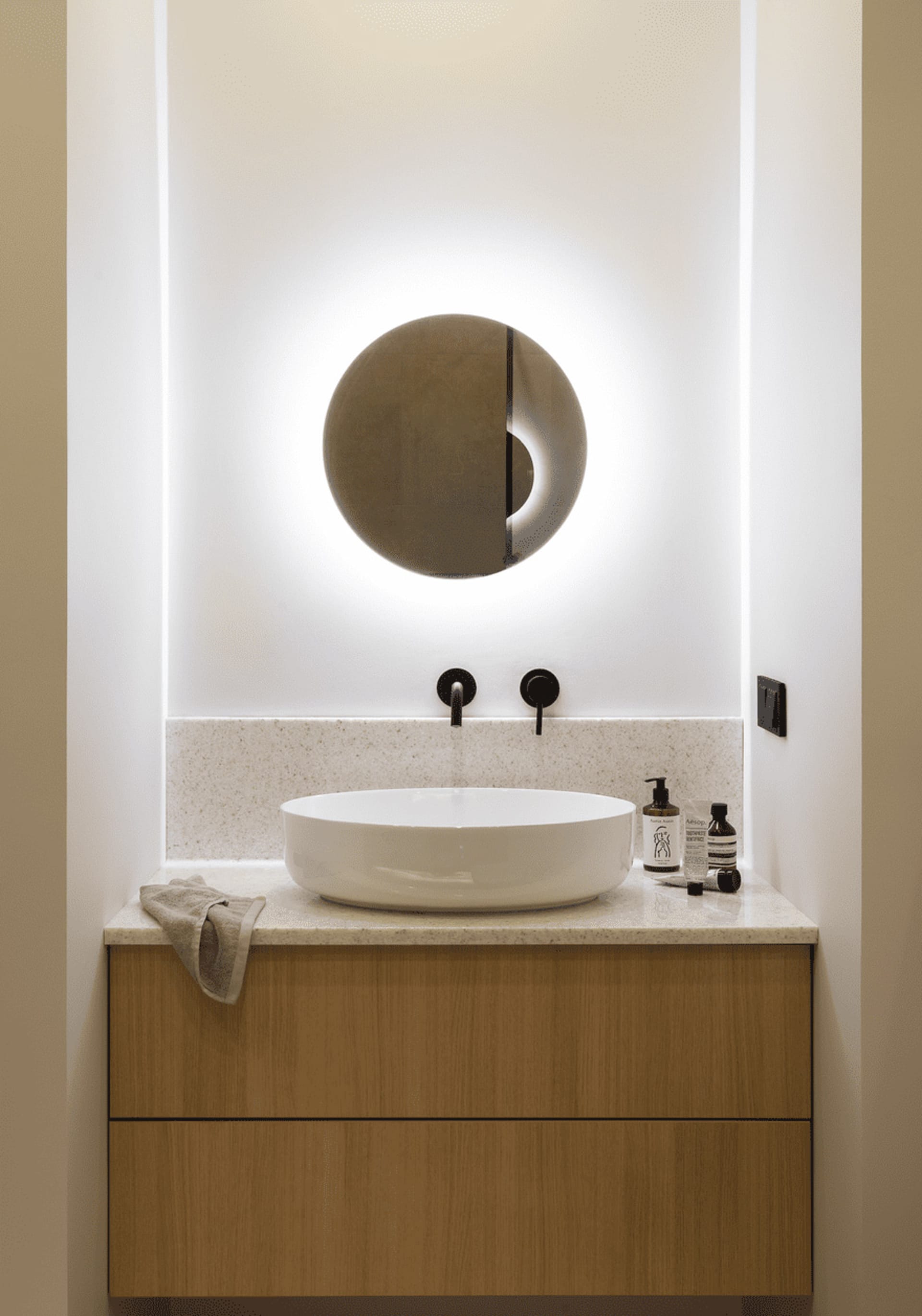 Modern bathroom with sink and marble counter, illuminated by ambient lighting.