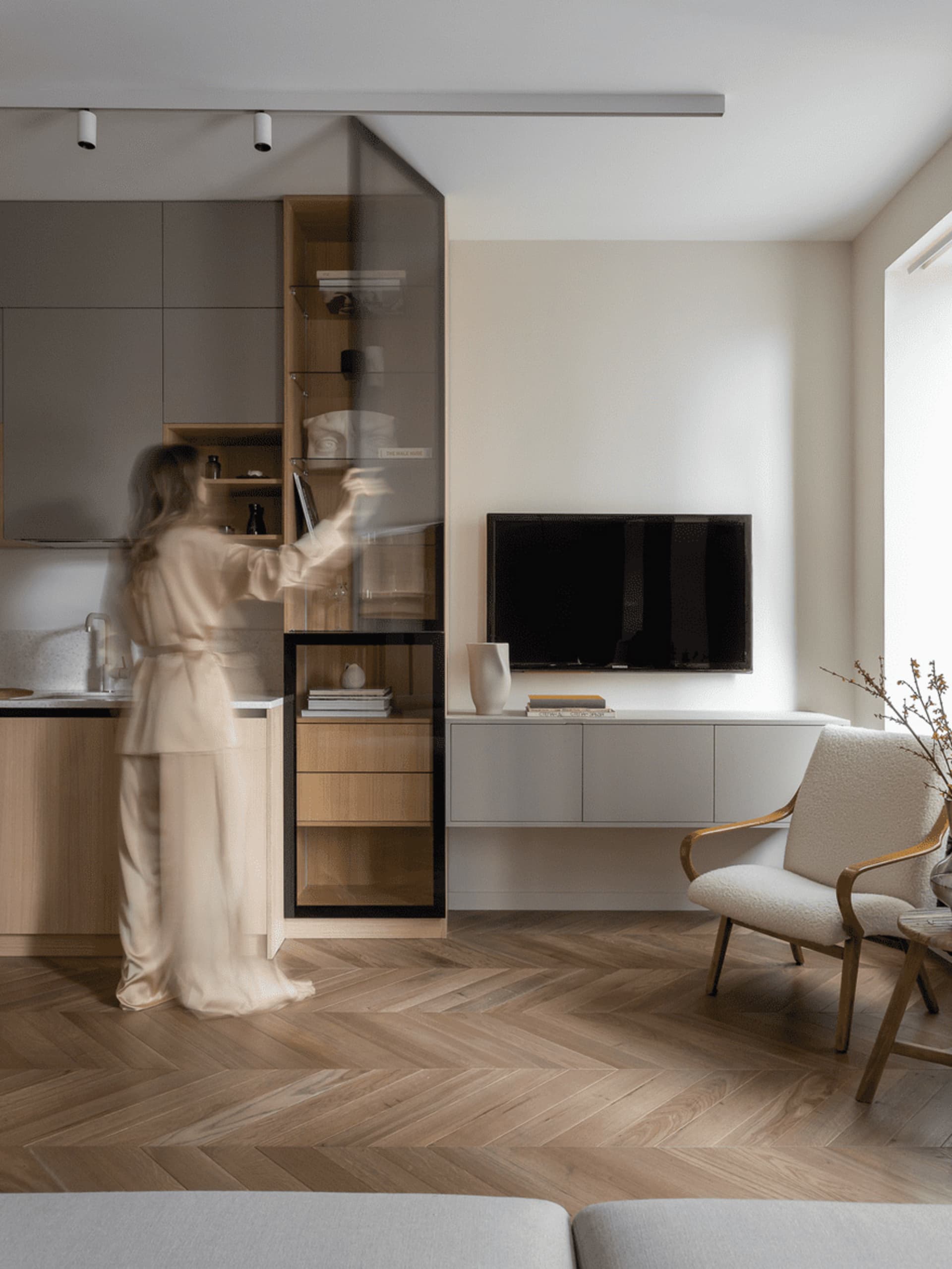 A modern living space featuring a combined kitchen and living area with minimalist design elements and a mix of wood, glass,