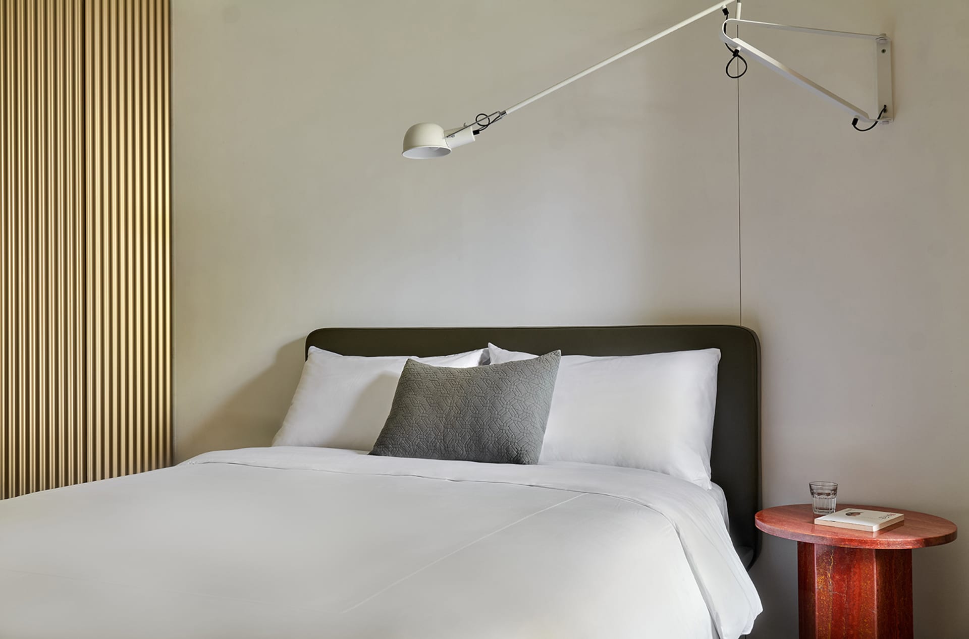 A minimalist bedroom featuring a white bed with a single decorative pillow.