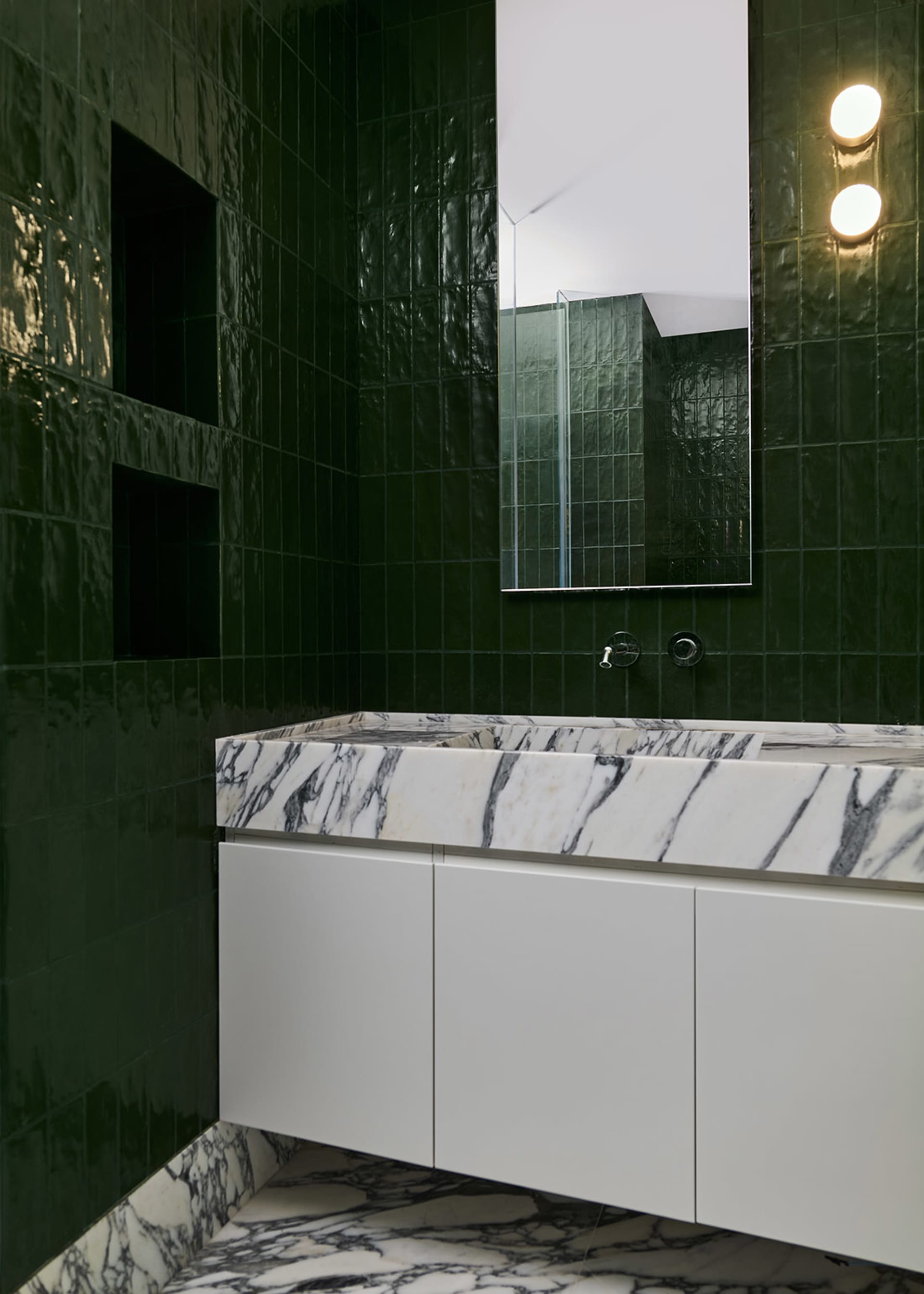 Modern bathroom featuring marble countertops on dark green tiles