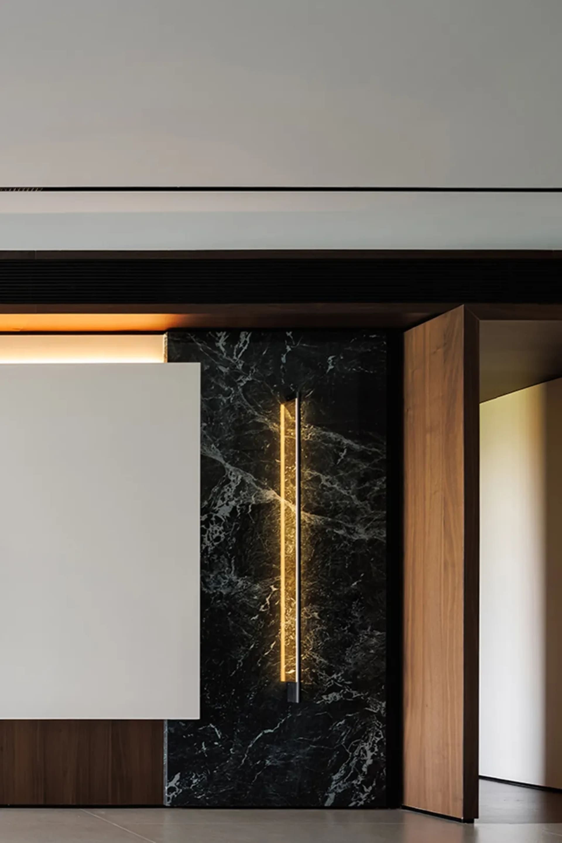 A modern interior space featuring a marble wall and wooden door.