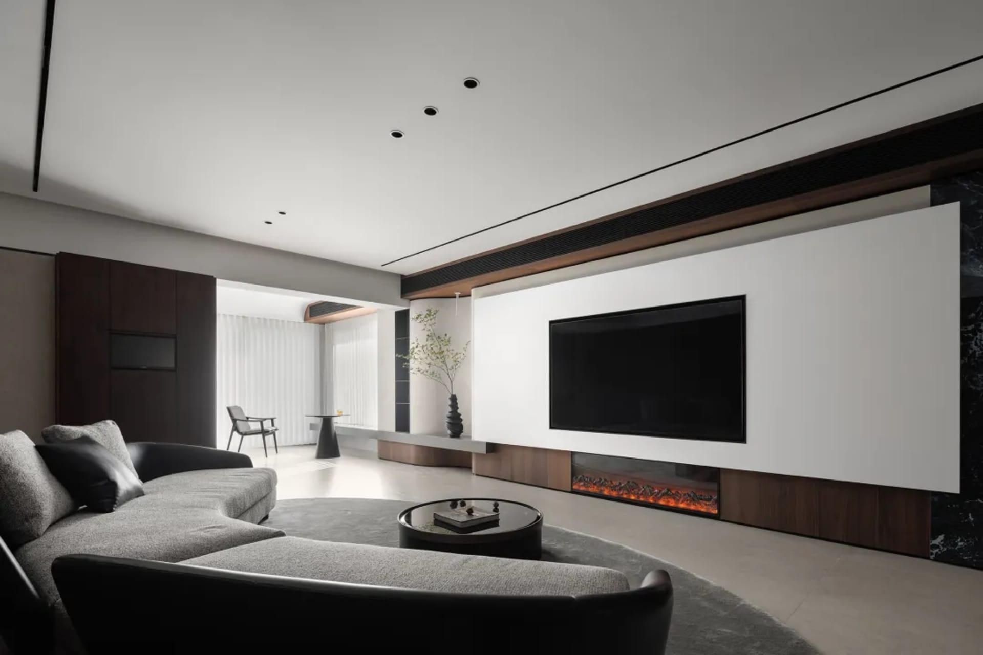 Modern living room with concrete walls, wood accents, and a large circular coffee table