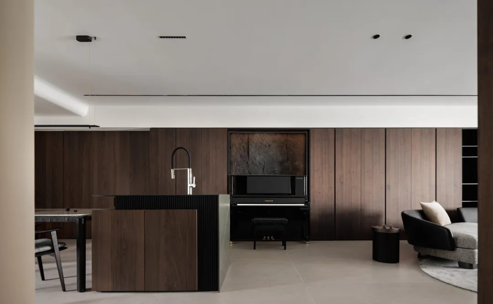 Modern living room featuring a black piano and sofa, styled with minimalist décor and hardwood flooring.
