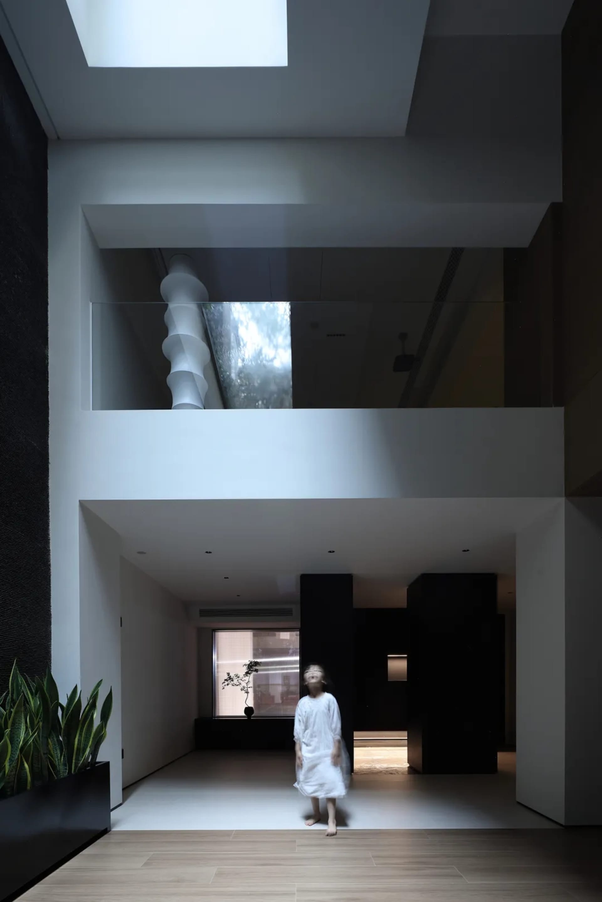 A modern living room with a glass wall featuring a spiral staircase.