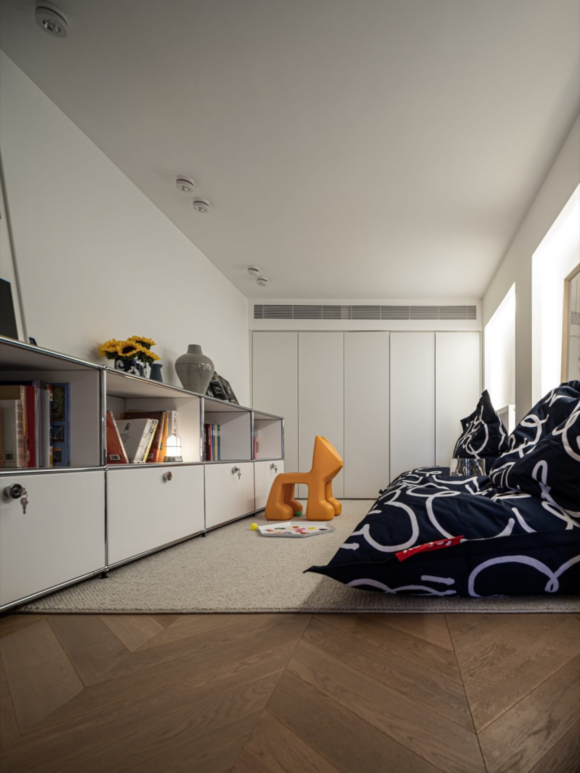 A modern living room with minimalist white furniture and wood flooring.