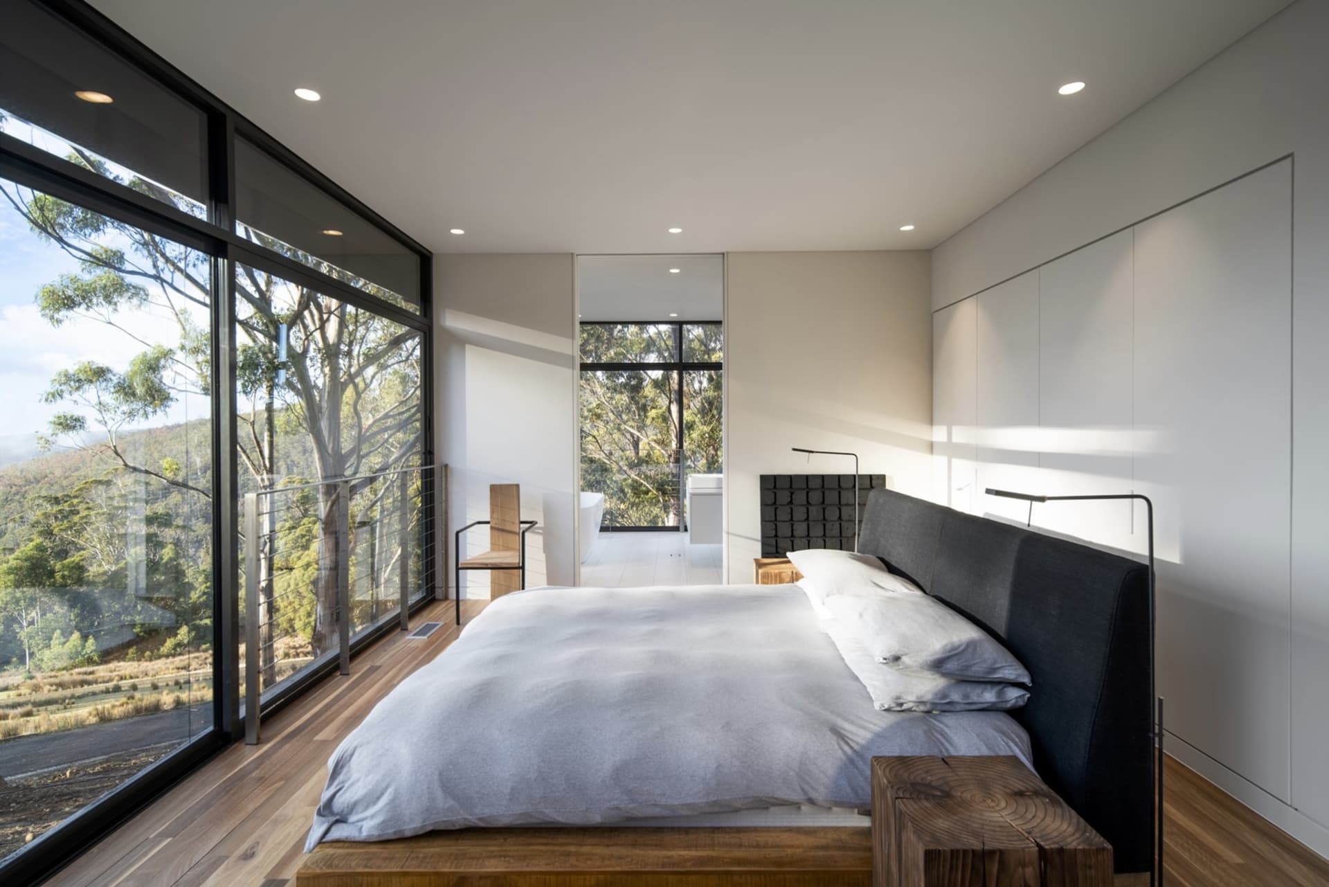 Modern bedroom with black accents, wood, and glass elements.