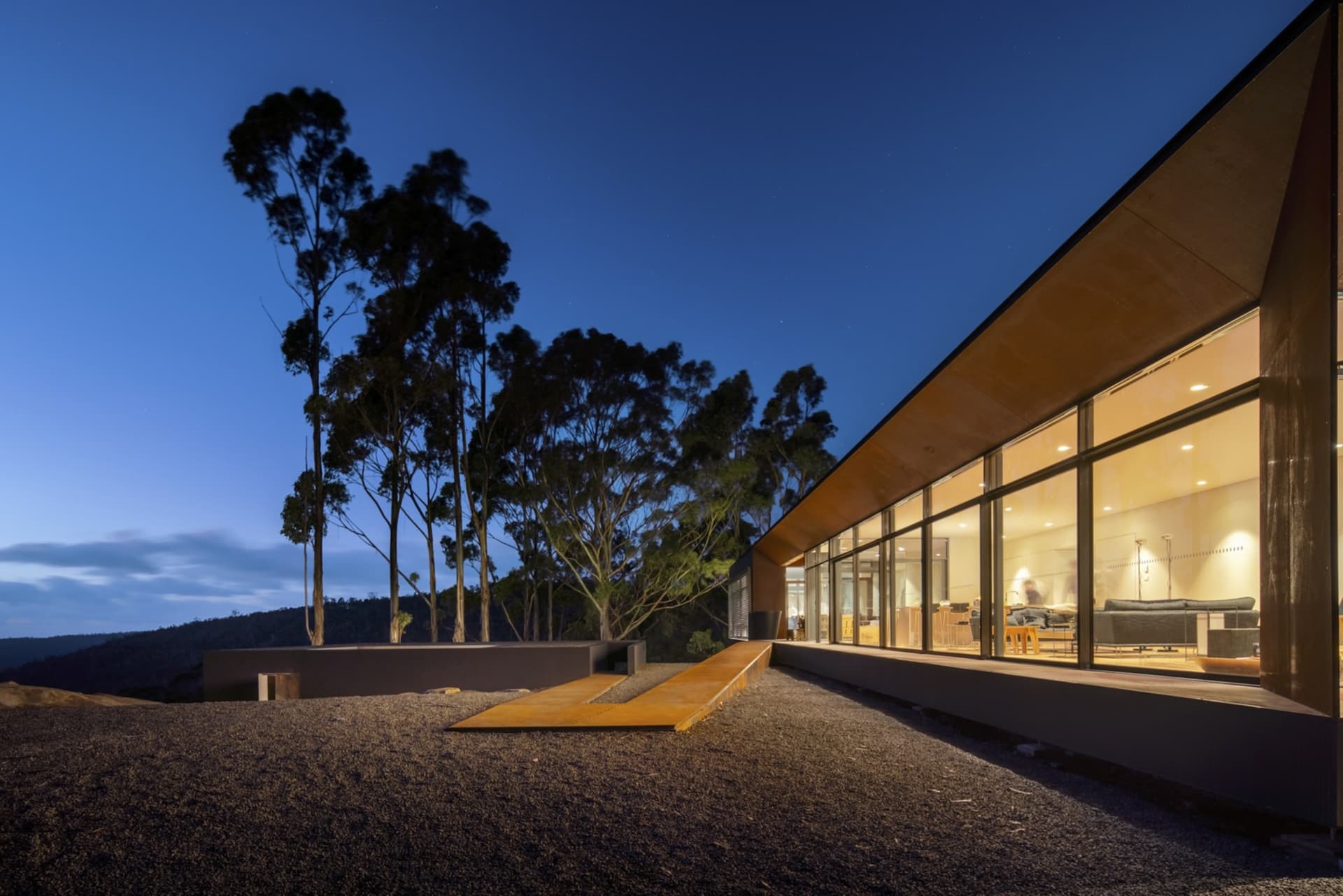 A modern house with metal cladding at dusk, featuring large windows and a minimalist design.