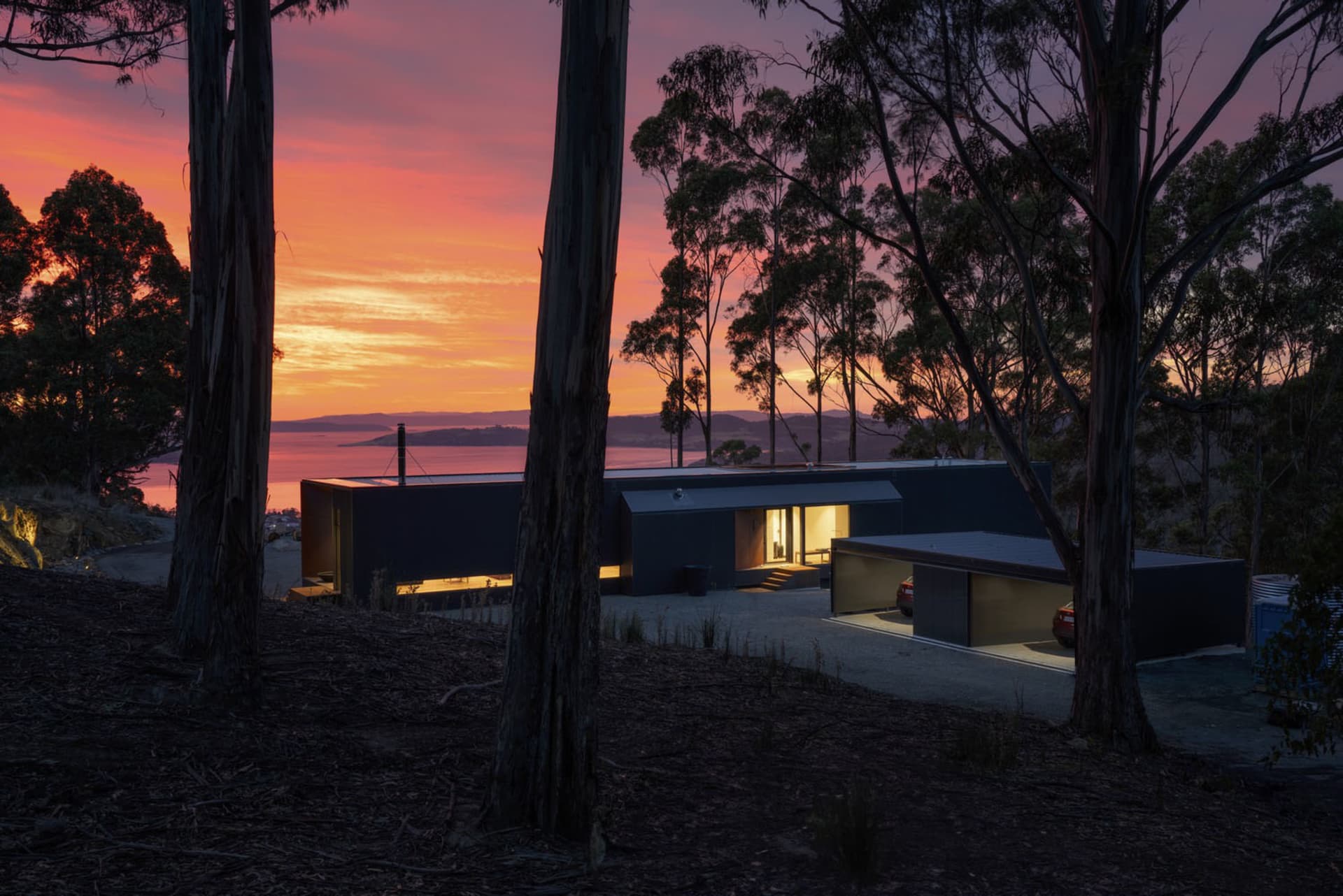 A modern house with metallic exterior during sunset with a view of the ocean.