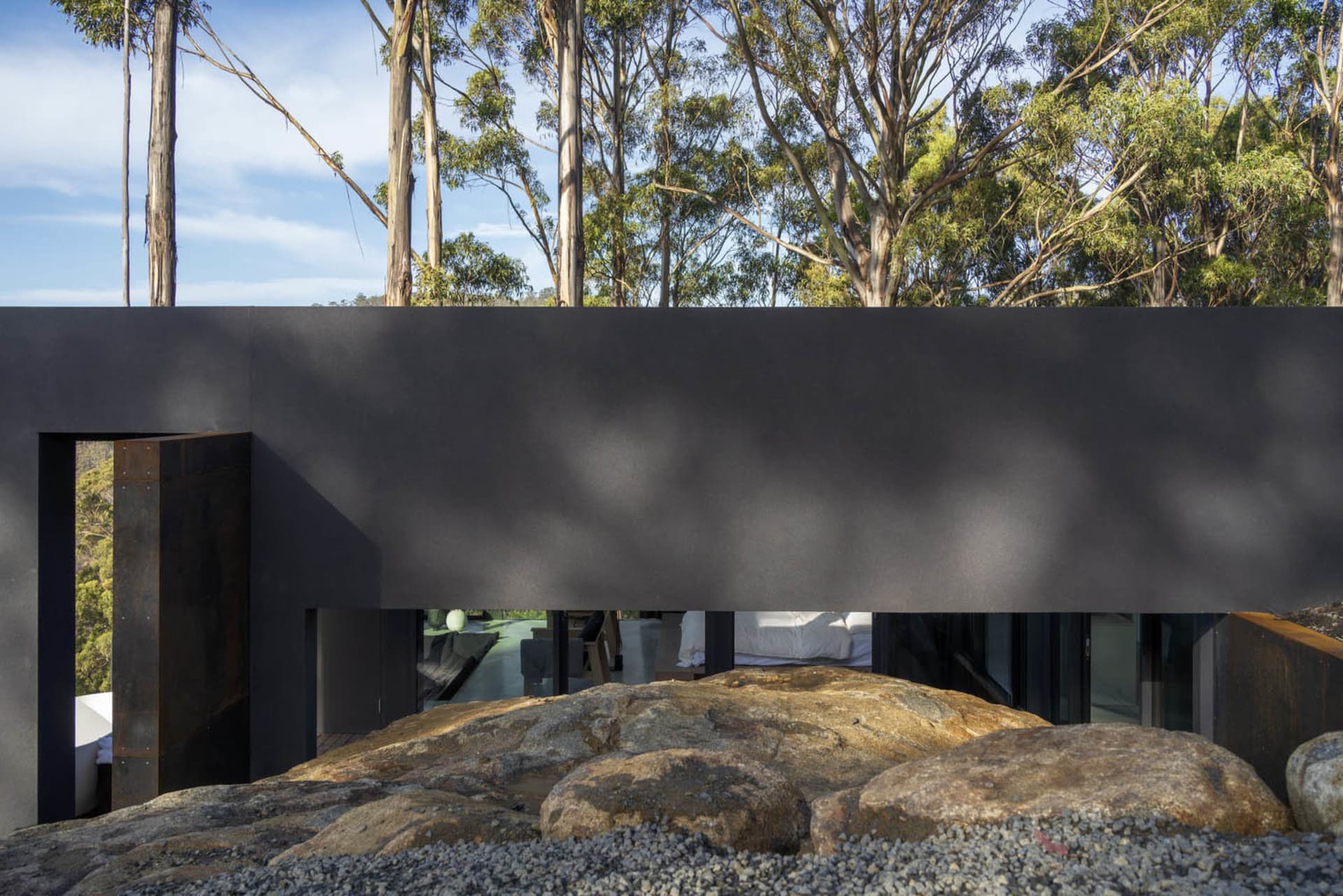 A minimalist residential house with concrete walls, surrounded by nature.