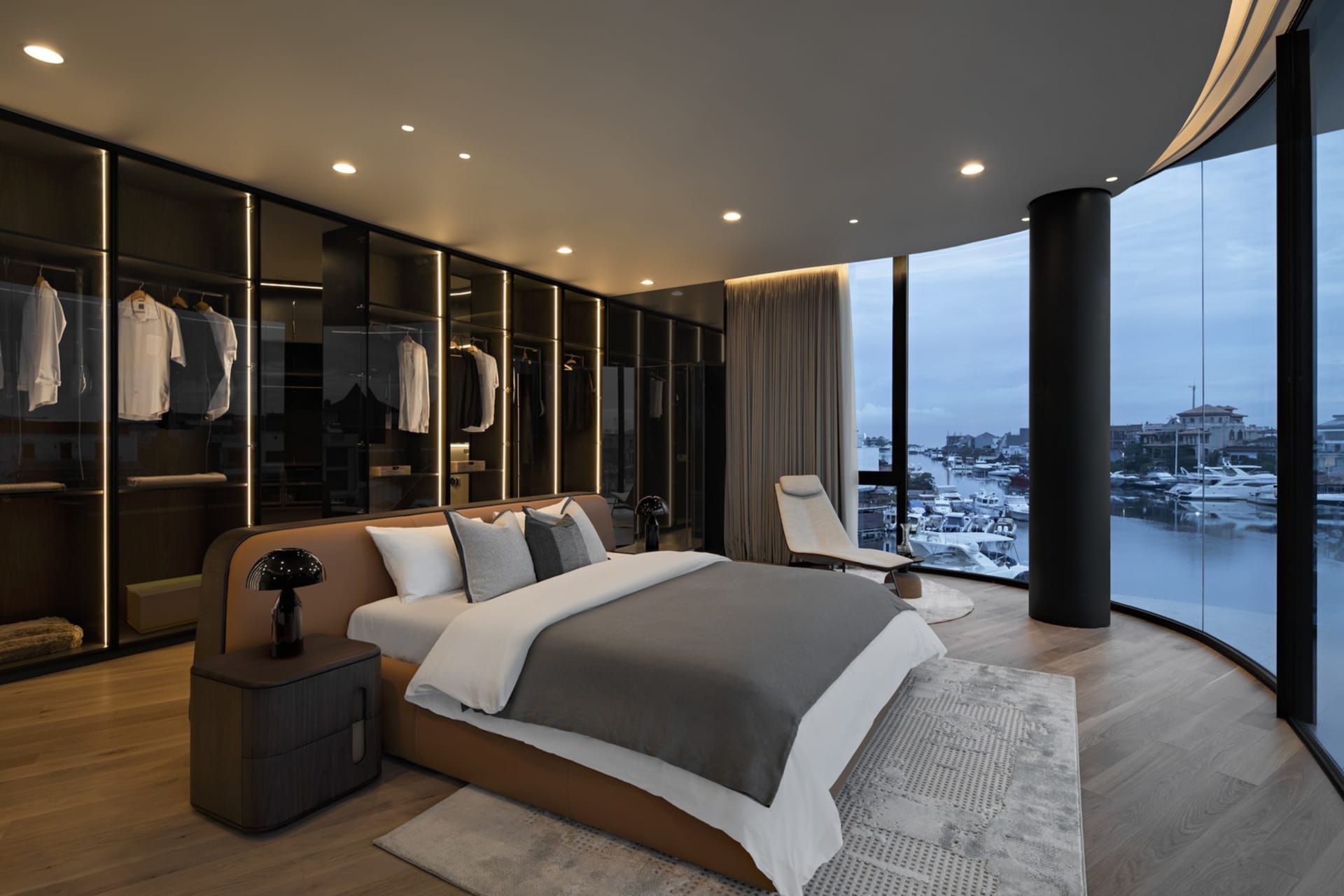 Modern bedroom with a large bed, metal headboard, glass doors, and wooden floors and furniture.