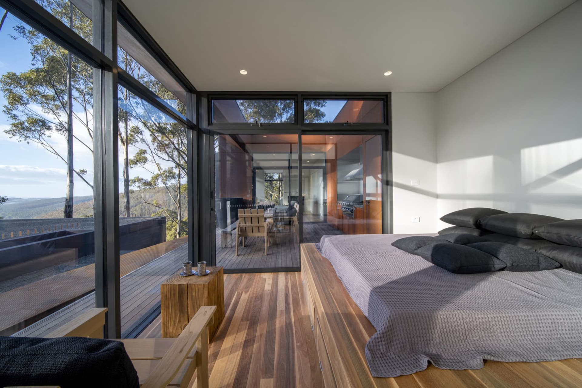 Modern residential bedroom featuring wood flooring and detailed furnishings with a view of the outdoors.