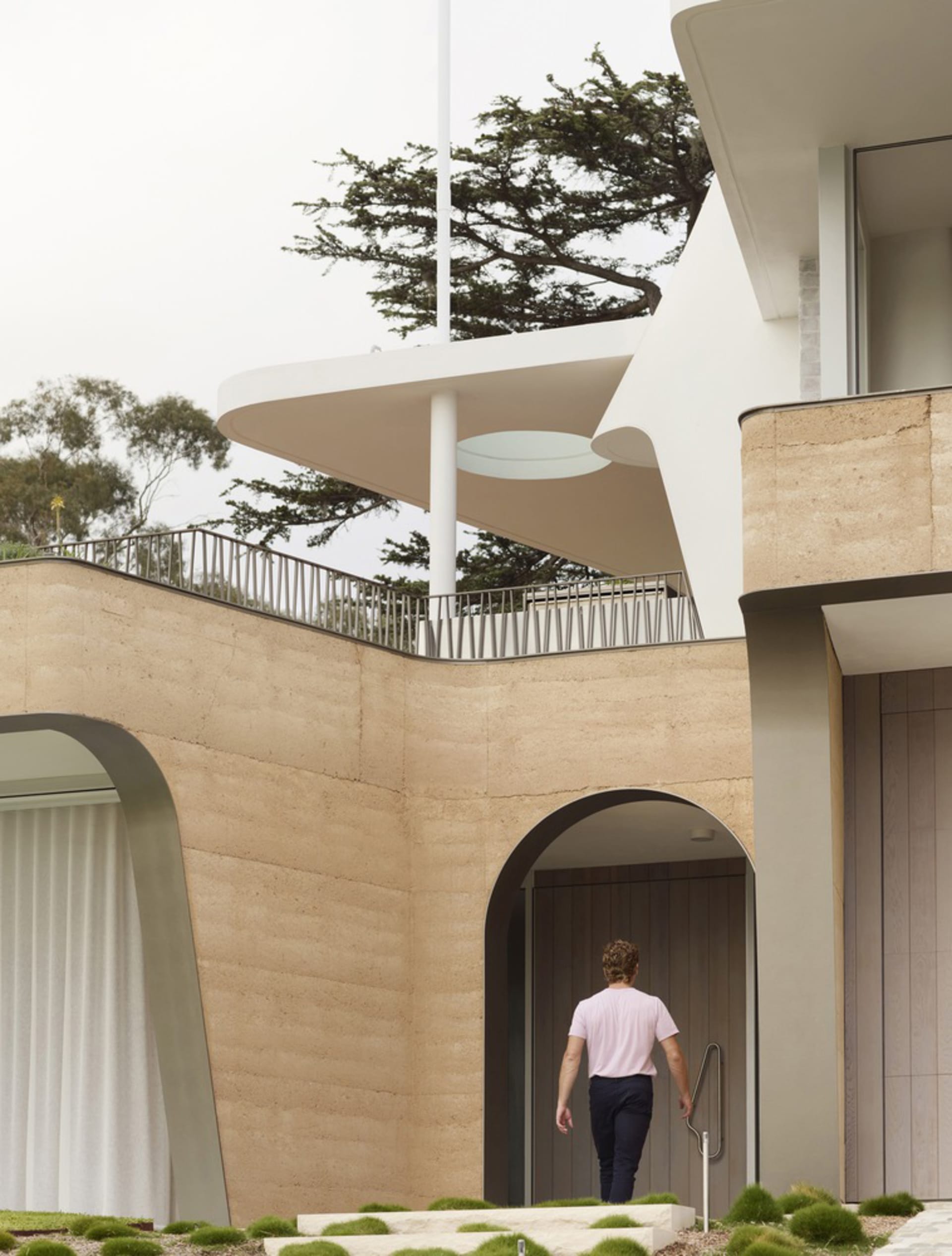 Modern residential entrance featuring a curved sandstone facade and architectural design.