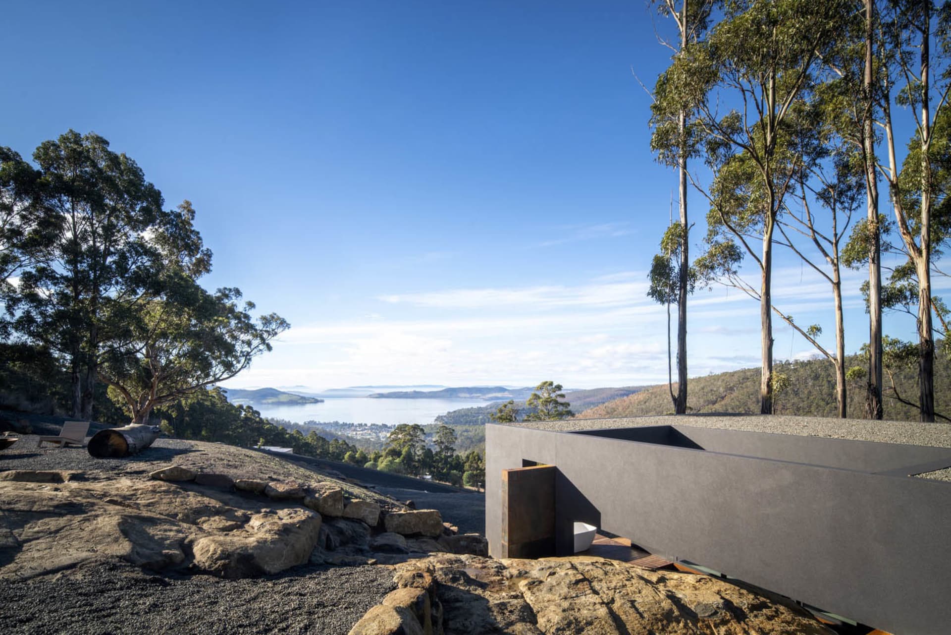 A contemporary residential exterior featuring grey stone, concrete, and metal elements.