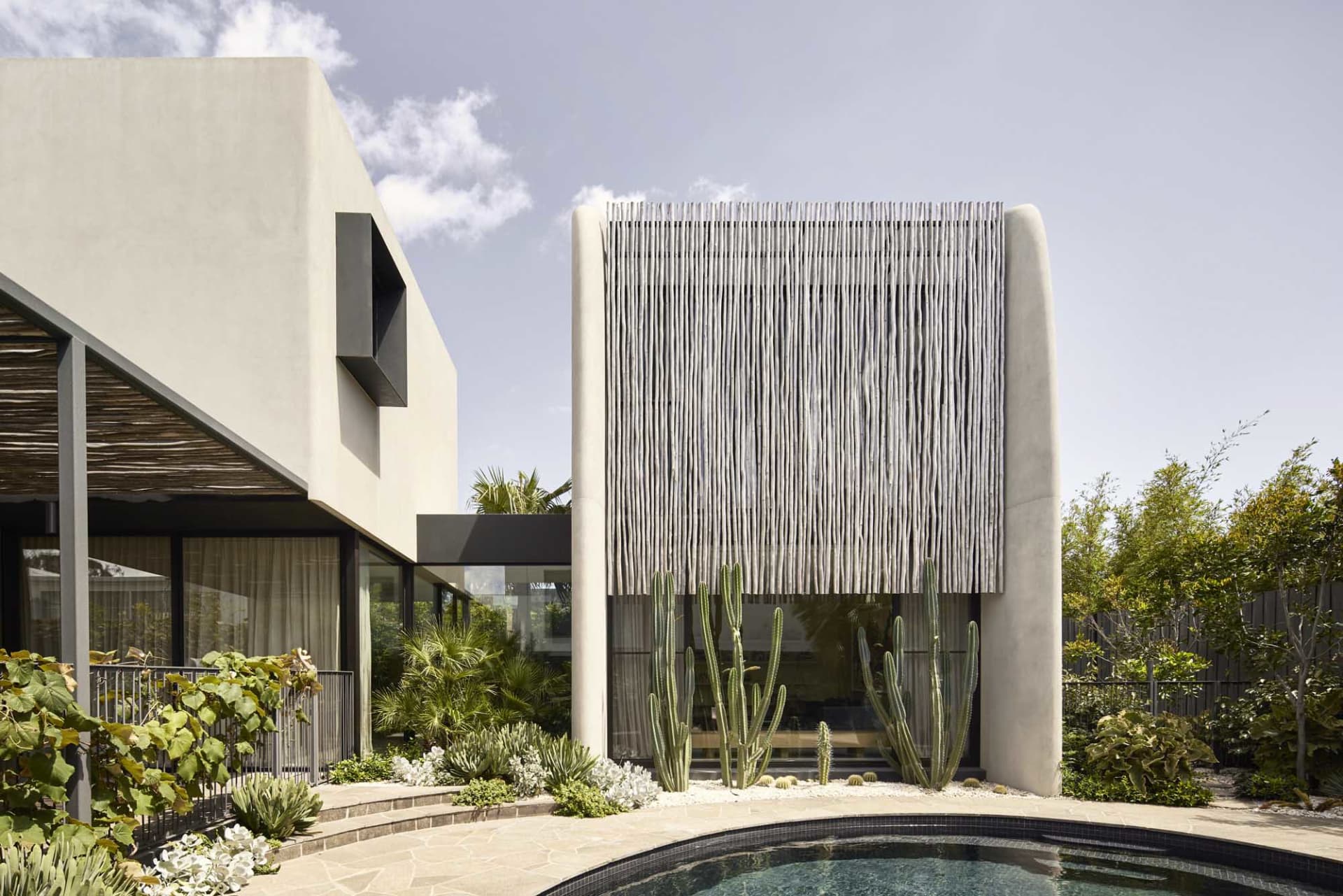 A modern concrete residence featuring cactus plants in its garden