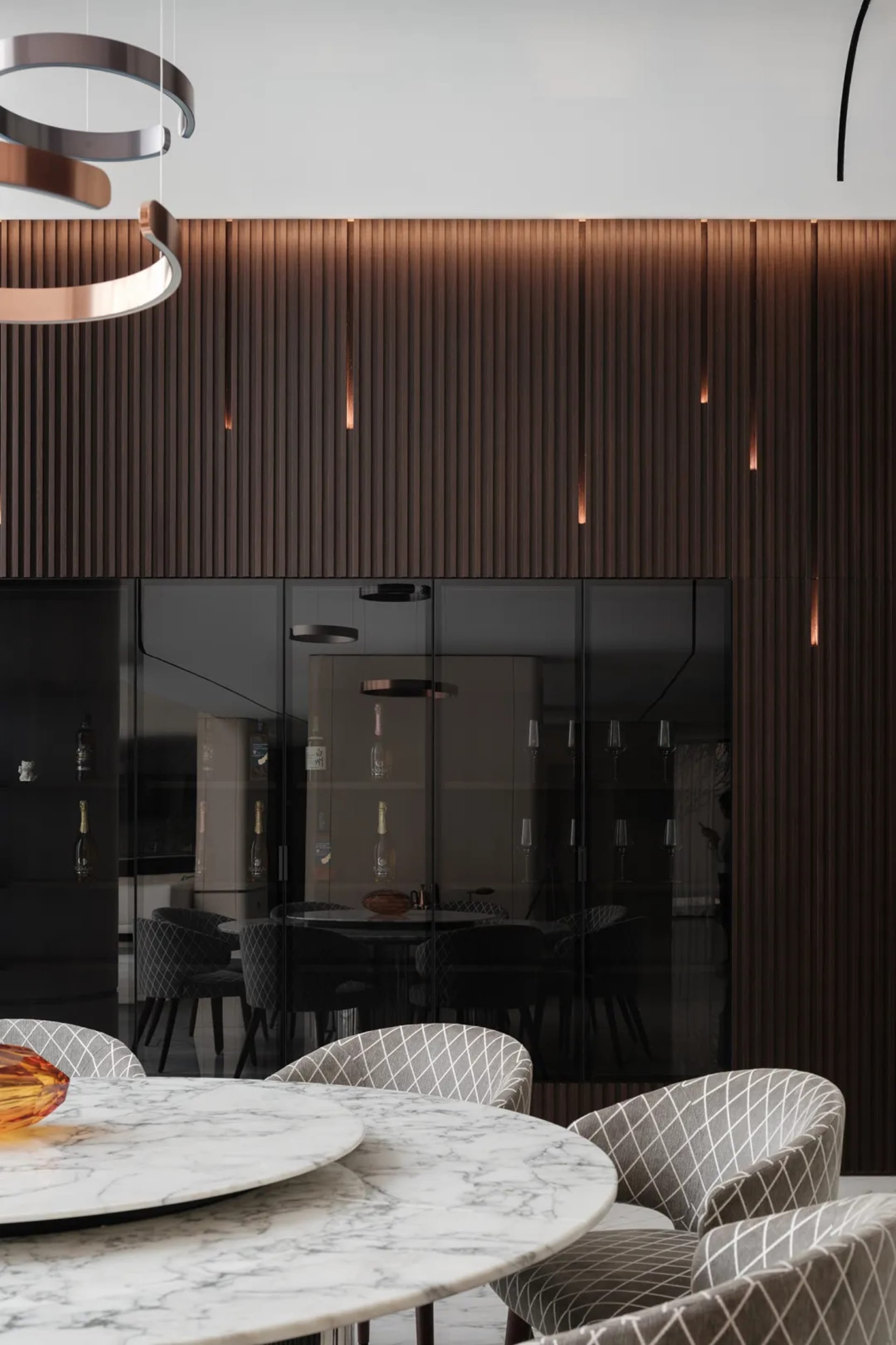 Modern dining room featuring a round marble table surrounded by upholstered chairs, with a wall of vertical wood panels and b