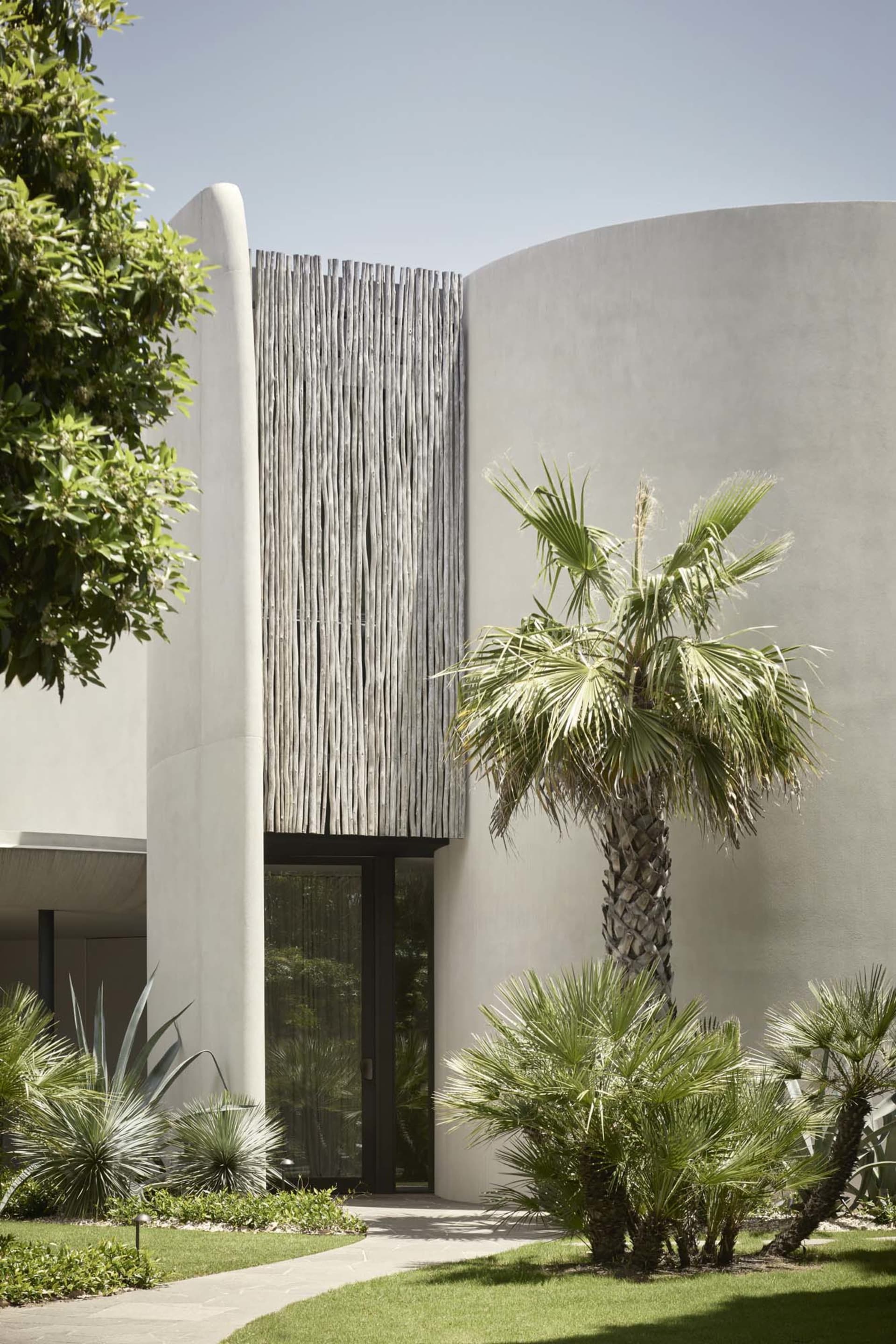 Modern architectural entrance featuring concrete walls and a wooden screen.