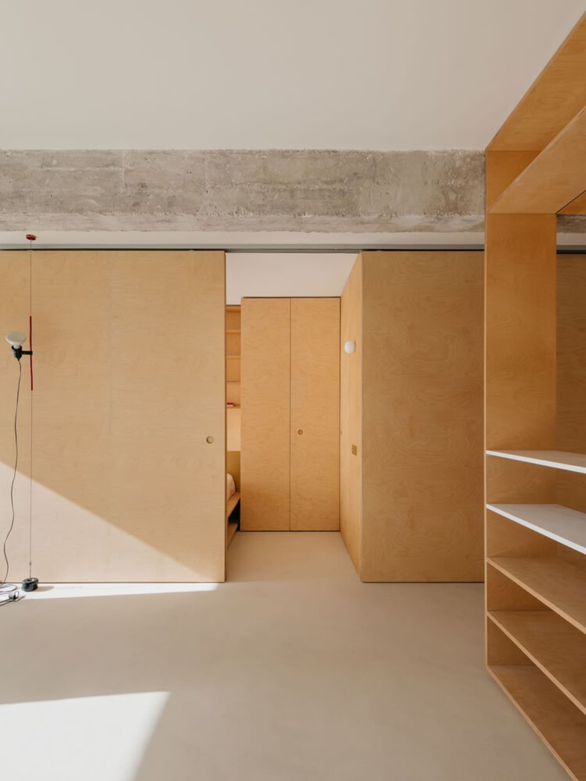 A minimalist room with wooden cabinets and concrete ceiling.