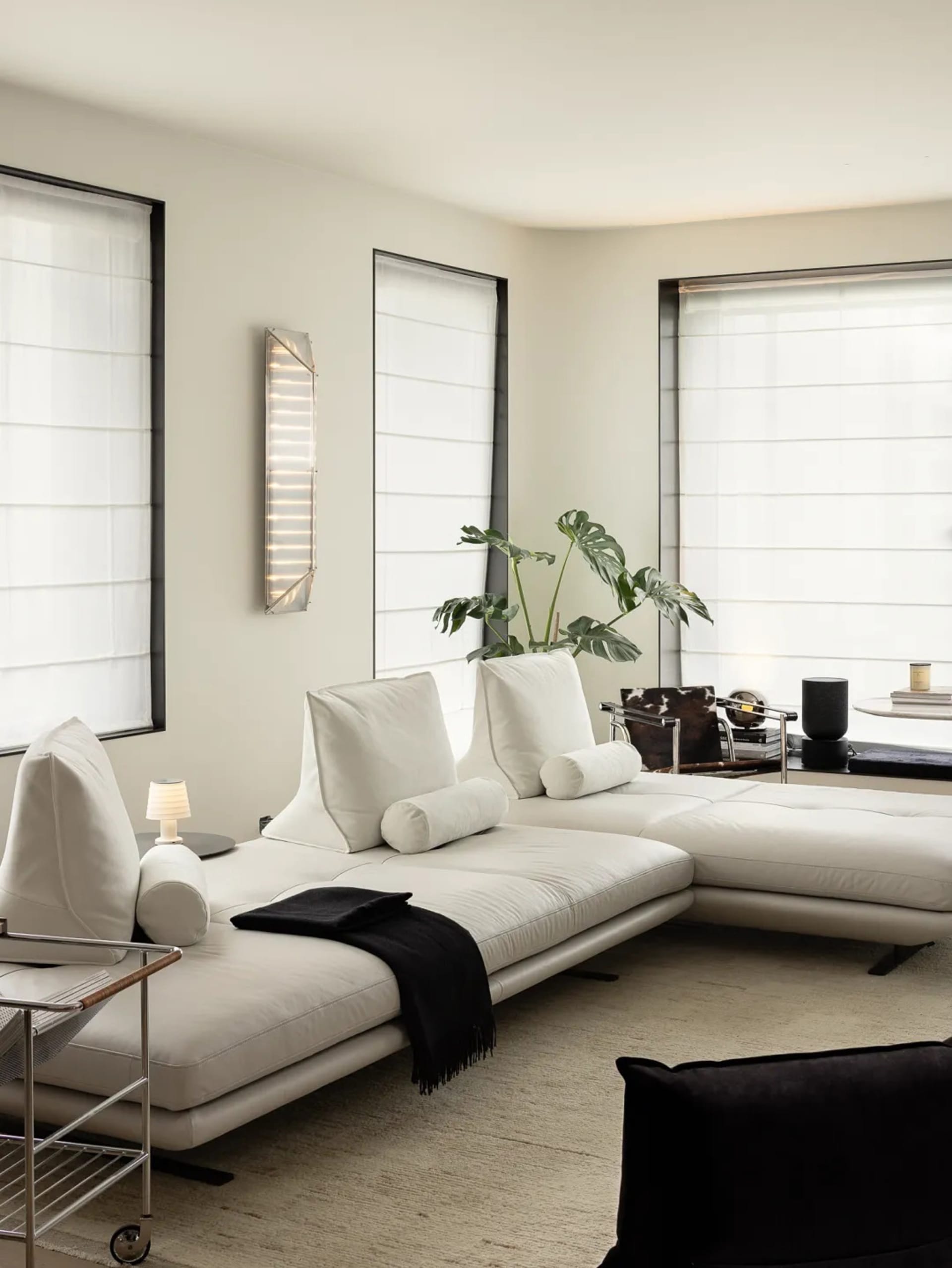 A modern white leather sofa in a living room with large windows and a minimalist design.