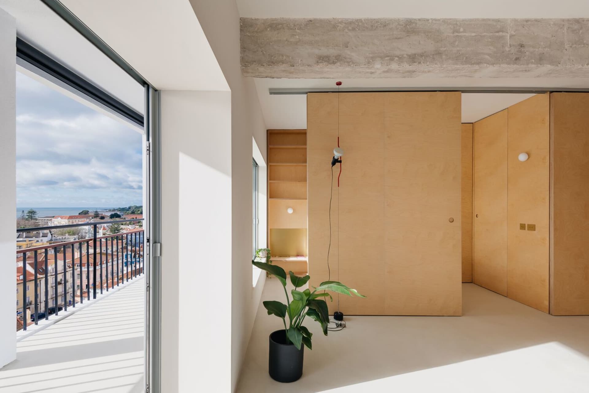 Modern minimalist living room with wooden walls and floor, large windows, and plants