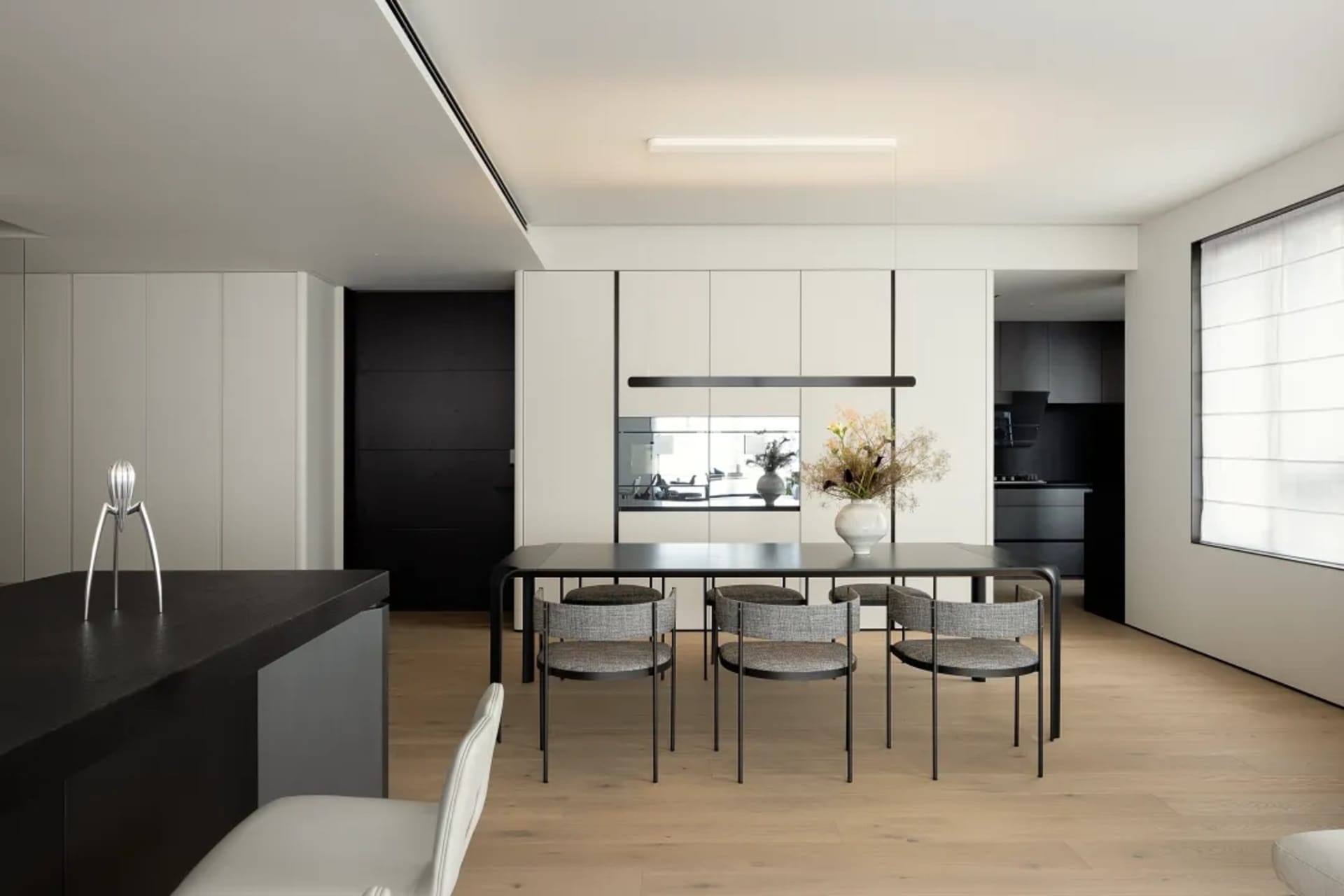Modern residential dining area with wooden flooring, metal dining table, and glass pendant light.
