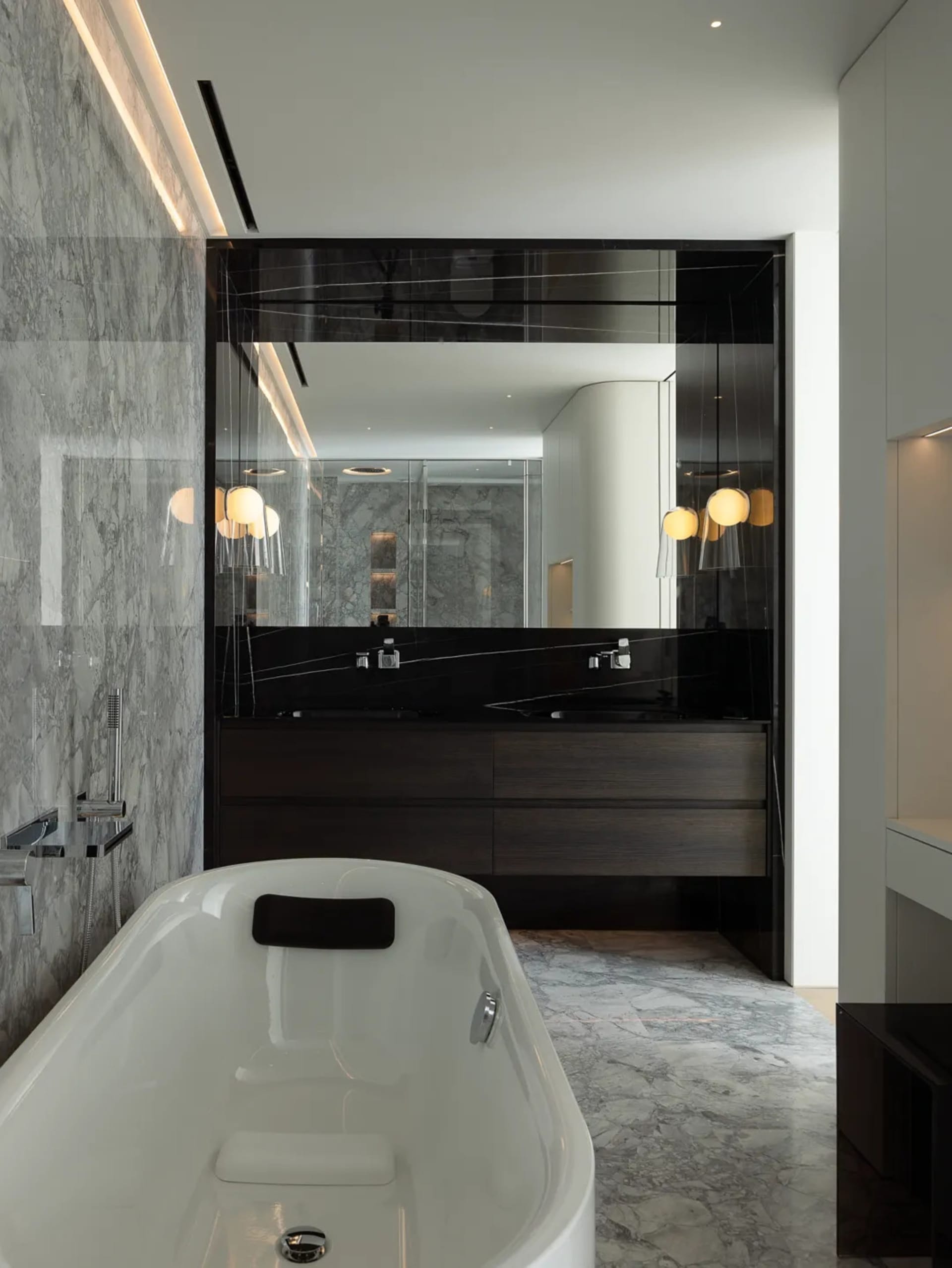 Modern bathroom interior featuring a freestanding bathtub, marble walls, and concrete accents.