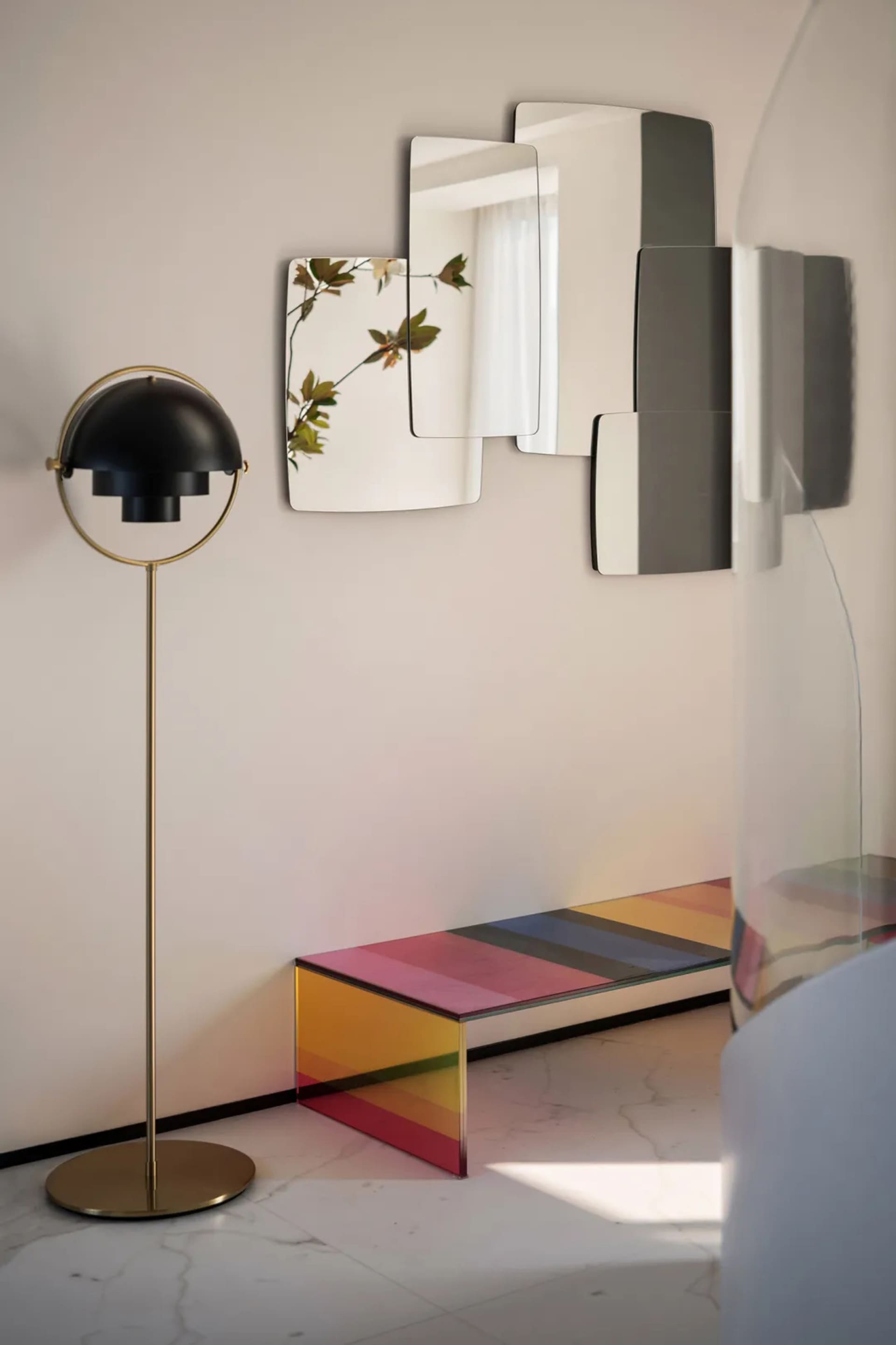 Modern living room featuring a multicolored glass coffee table with geometric patterns, a standing lamp with a spherical shad