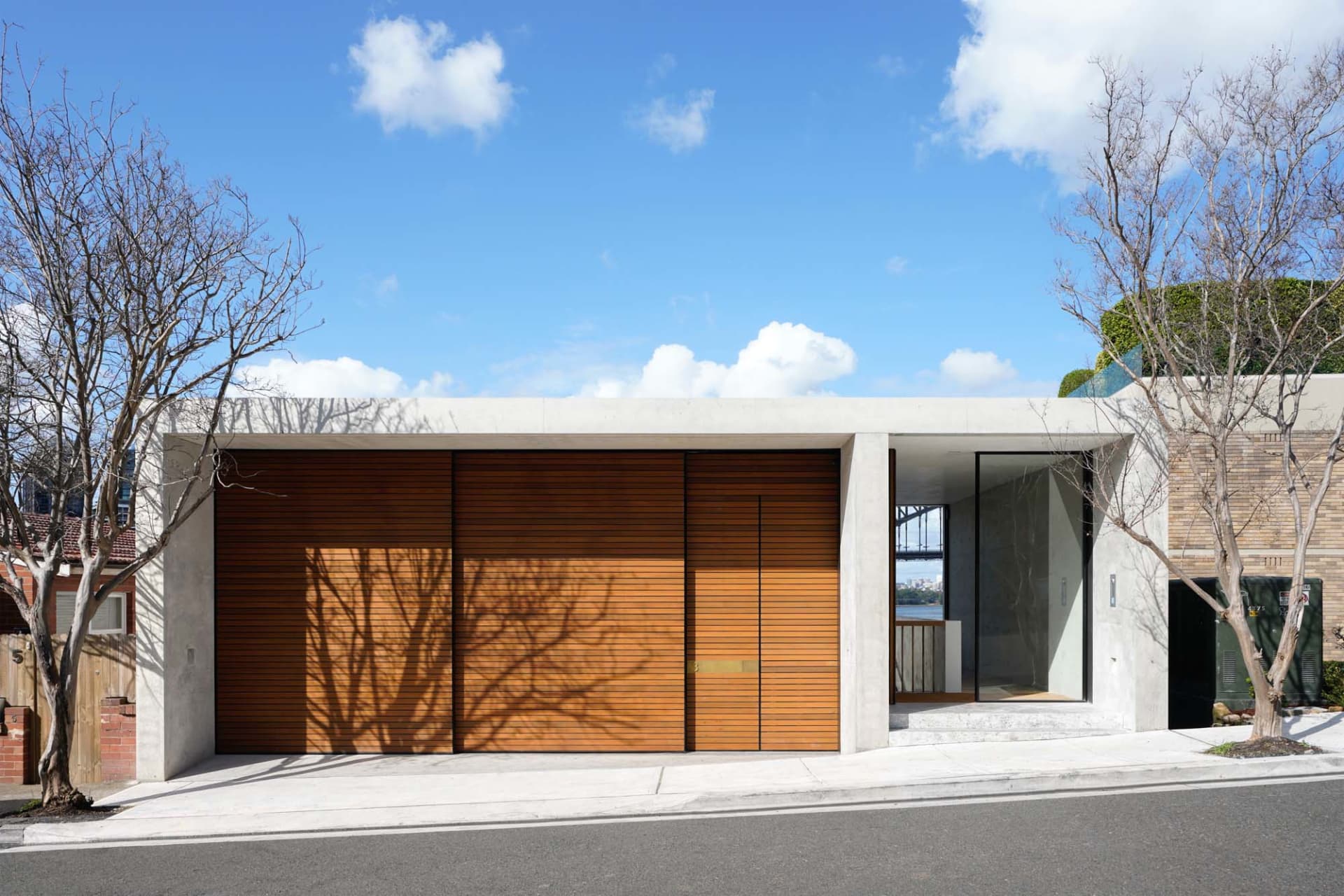 Modern residential entrance with concrete frame, glass wall, and wooden sliding doors.