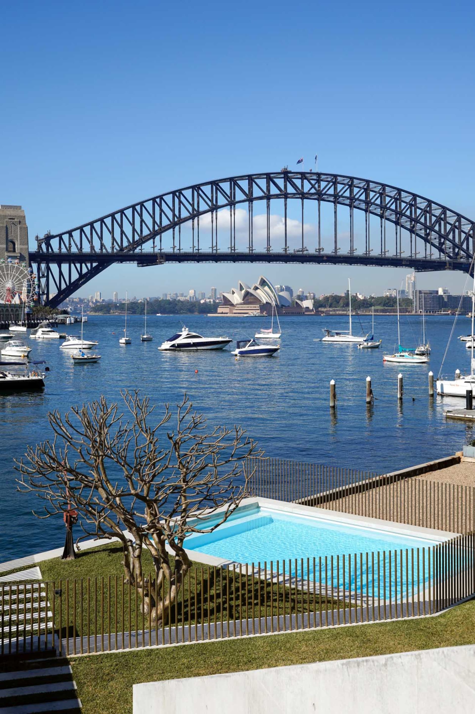 A view of a cityscape featuring a metal bridge over a body of water with several boats.