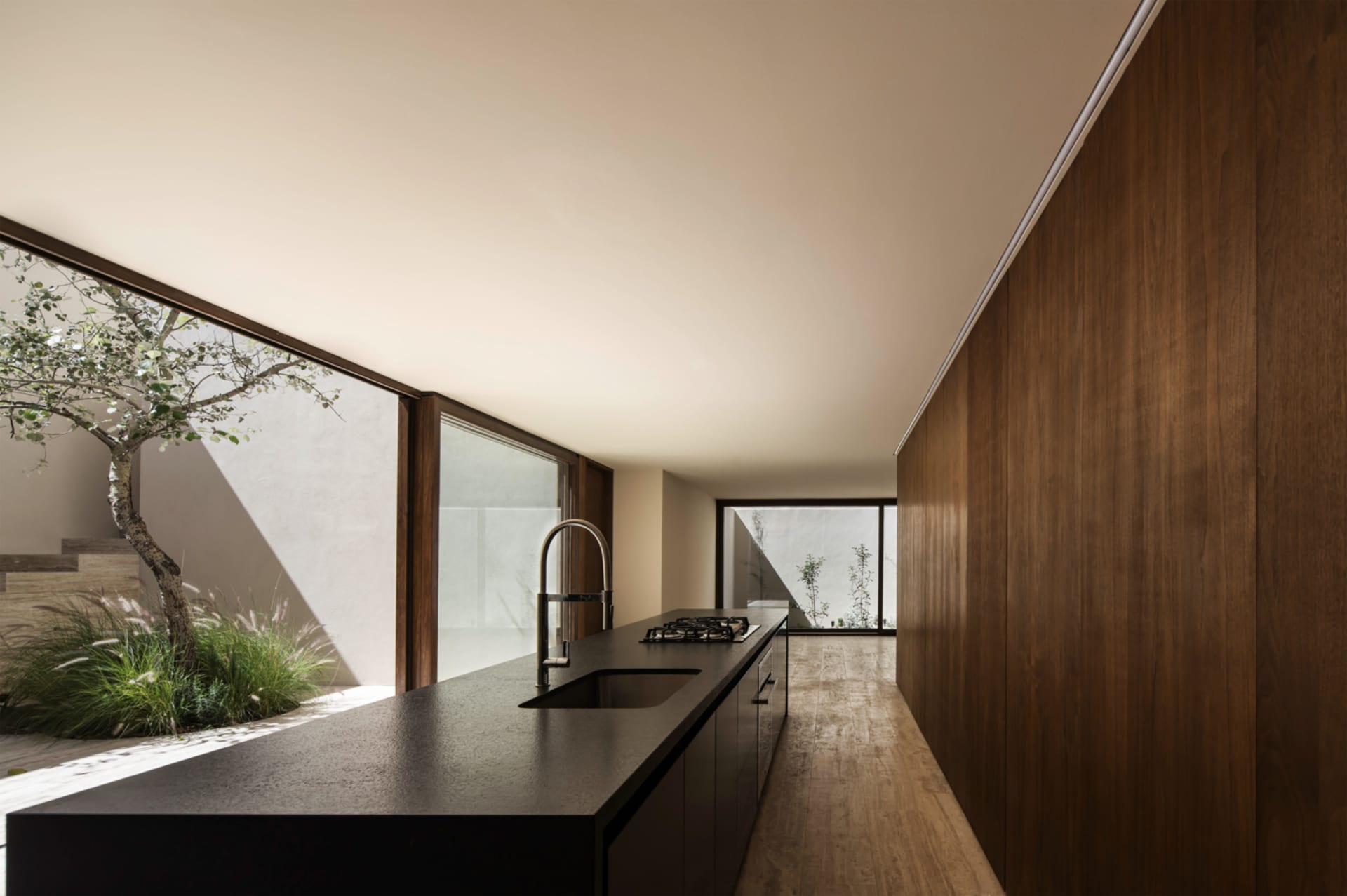 Modern kitchen with black countertops and wooden cabinets, featuring a sink and stove.