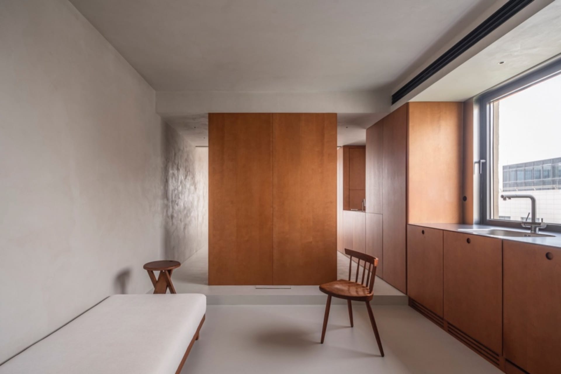 Minimalist apartment kitchen featuring wooden cabinets and a white floor.
