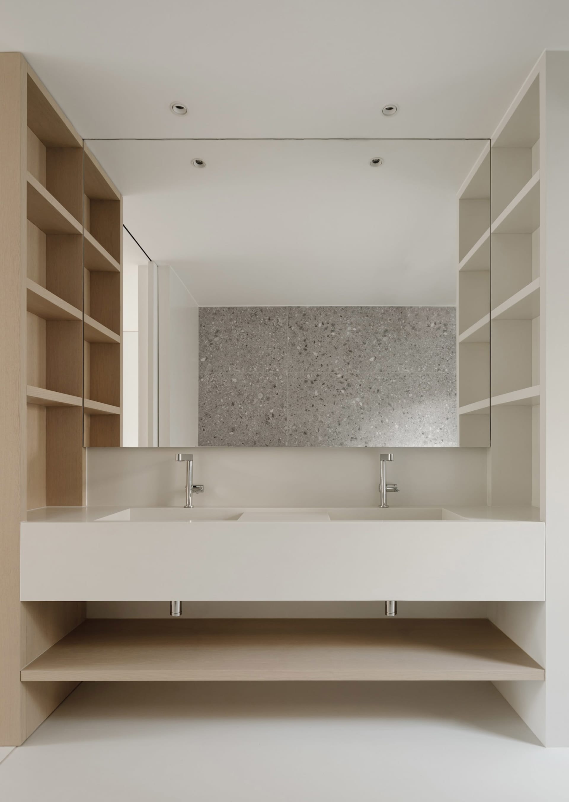 A minimalist modern bathroom with a white floating vanity, concrete countertop, and large mirror.